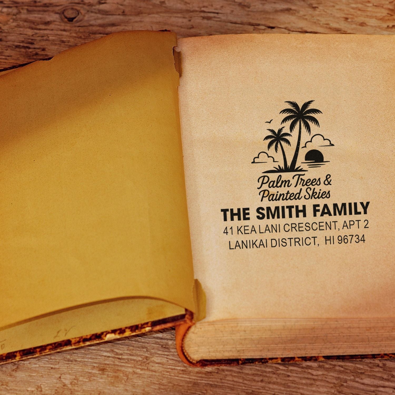 Personalized rubber address stamp with palm tree logo and family name, stamped in an open book.