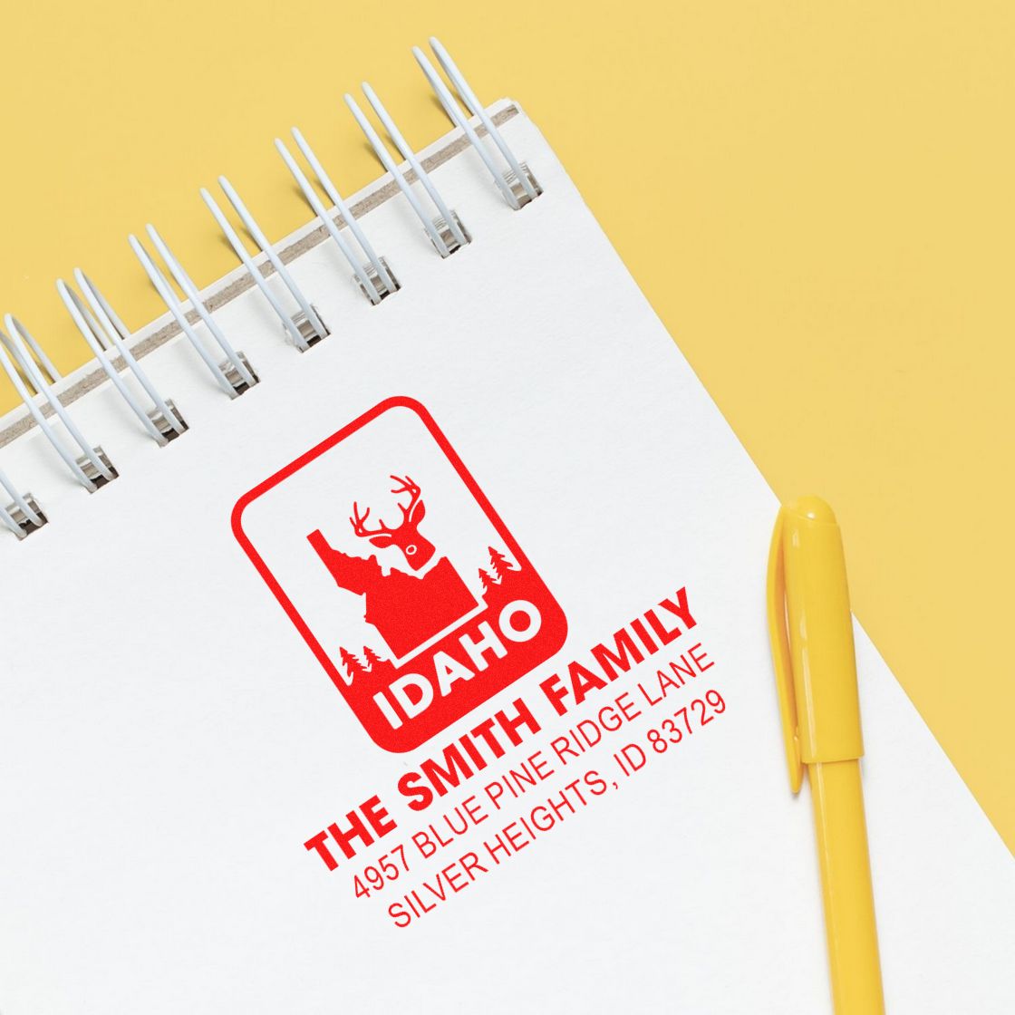 Personalized Idaho family return address rubber stamp on notebook with deer logo and yellow pen.