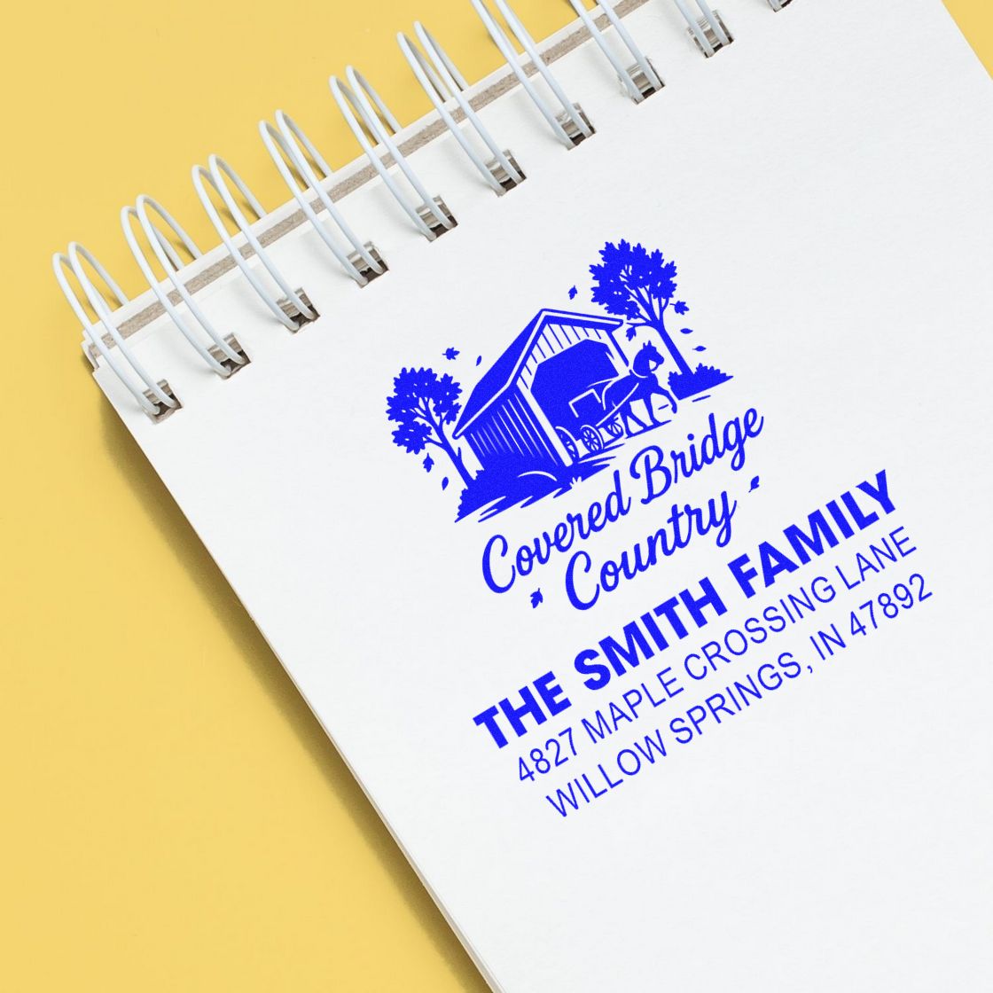 Custom rubber stamp for Covered Bridge Country family address, showing logo and return address on a notebook page.