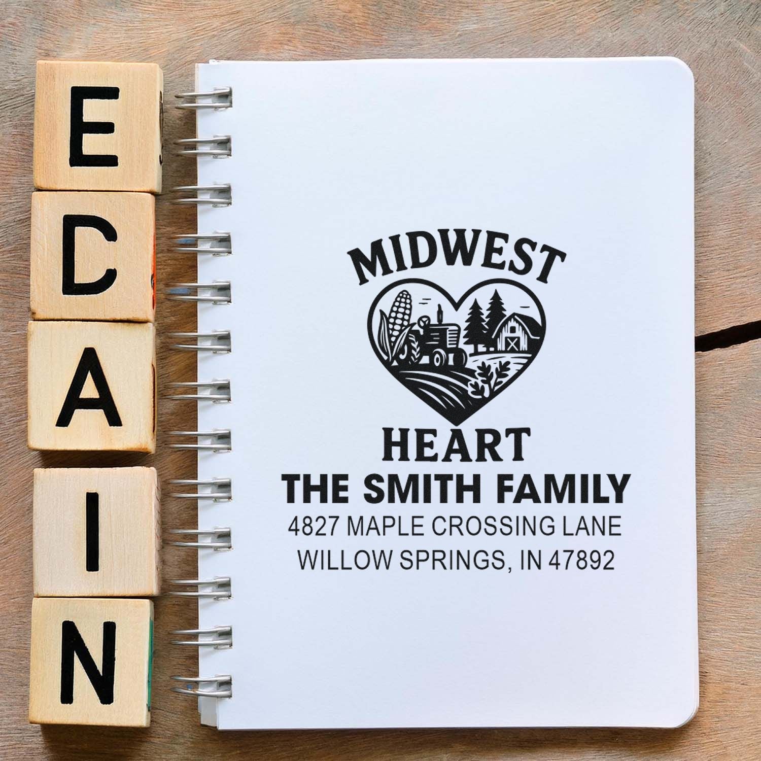 Custom return address rubber stamp with Midwest heart design for The Smith Family, beside wooden alphabet stamp blocks.