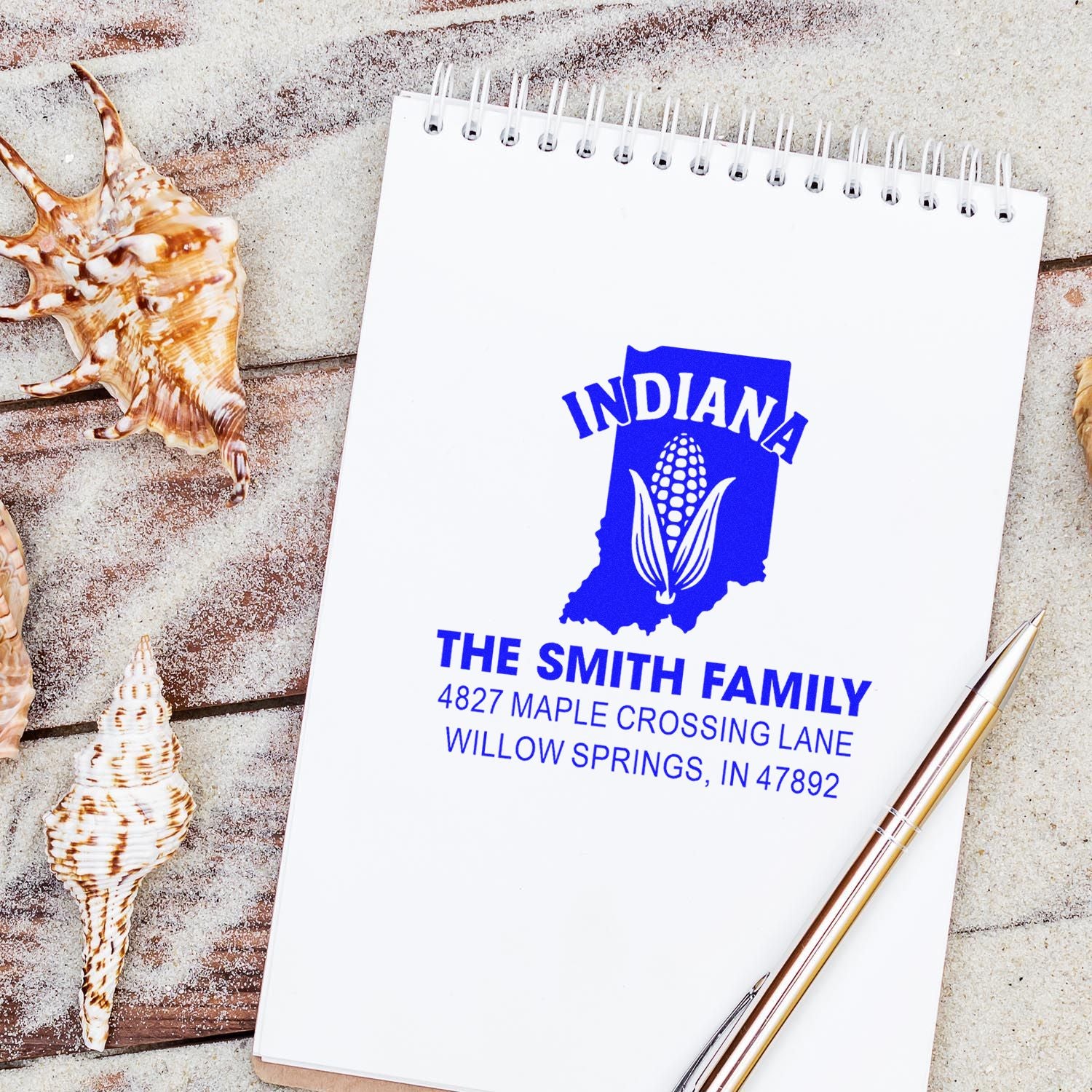 Custom Indiana return address rubber stamp with family name, address, and corn logo on a notebook mockup.