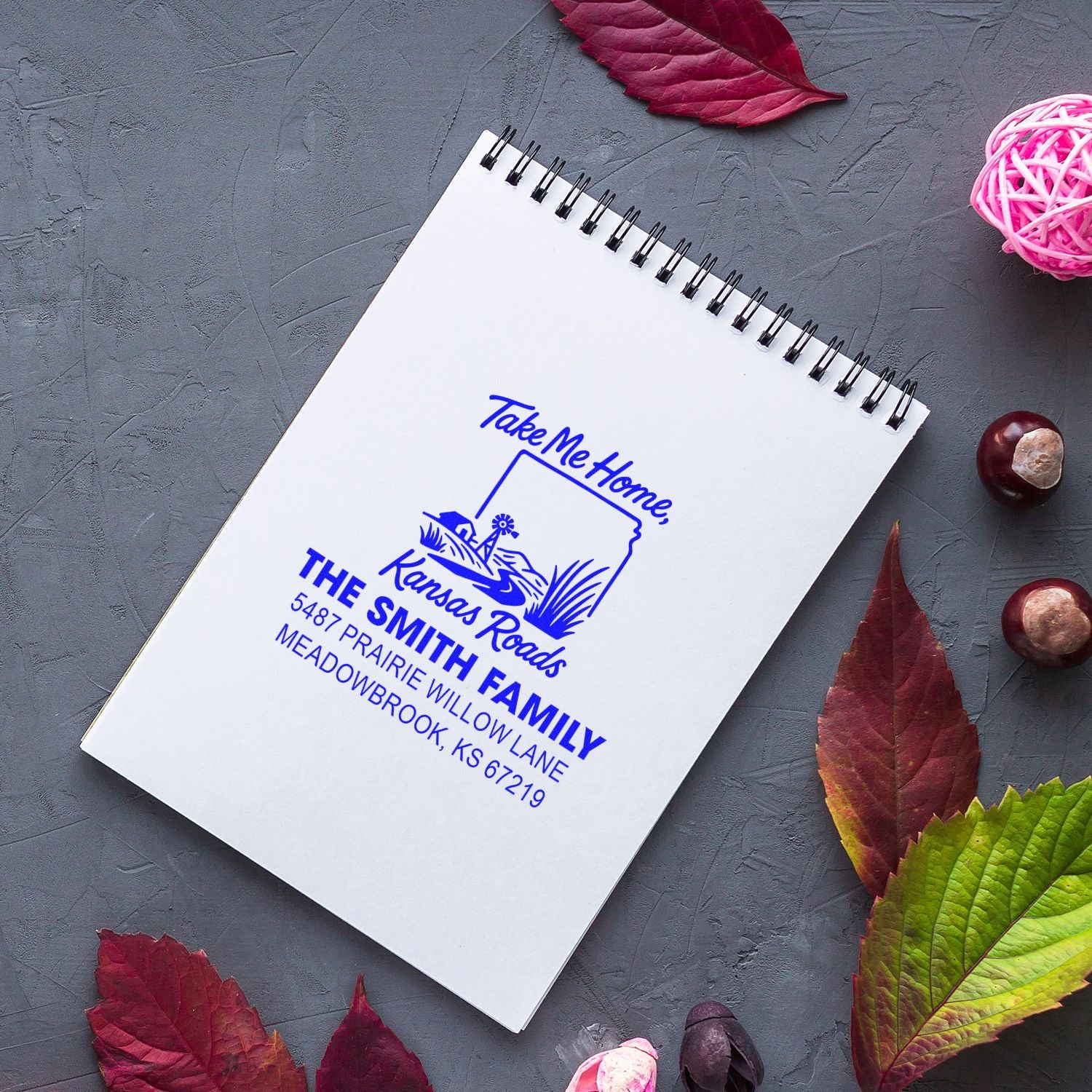 Custom family return address rubber stamp on notebook, featuring Kansas Roads design for personalized mail and crafts.
