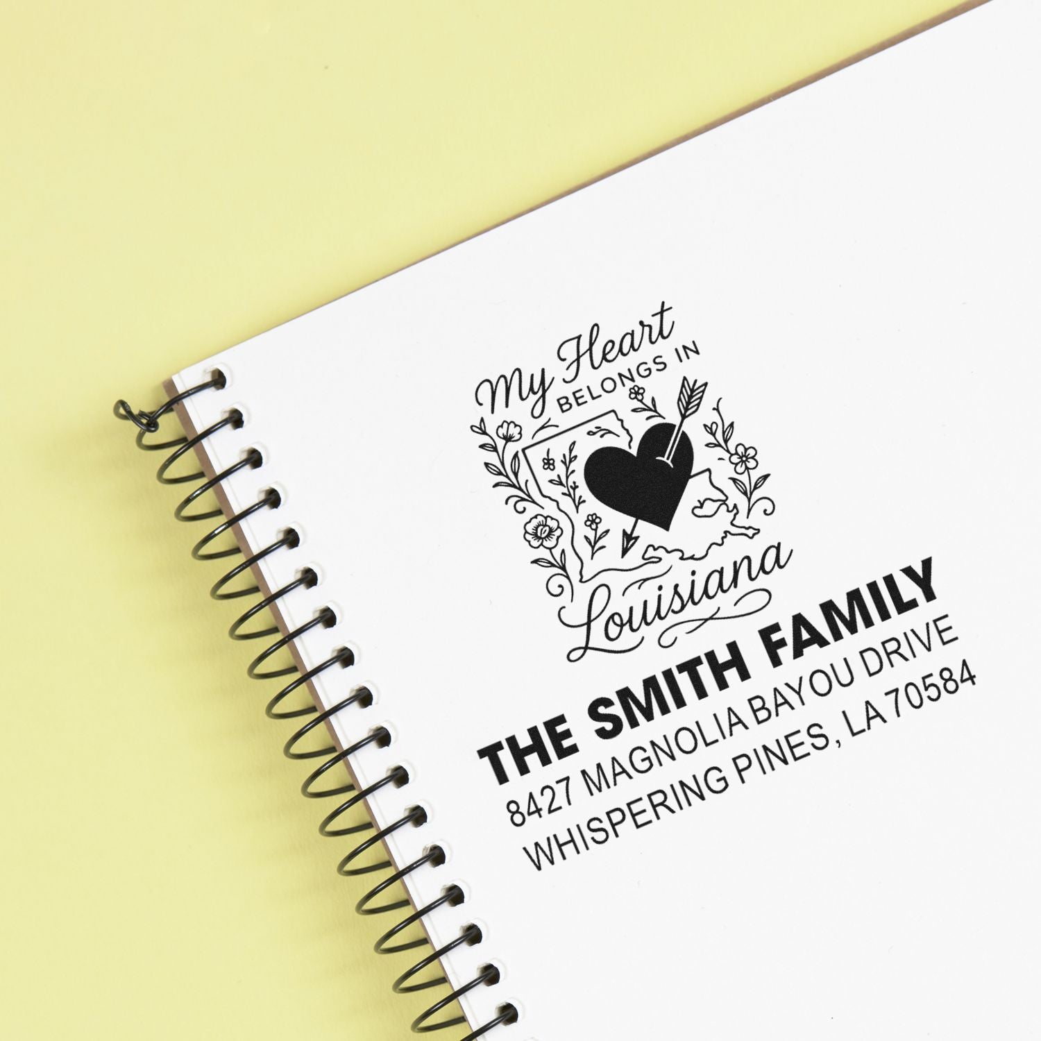 Custom return address rubber stamp impression on spiral notebook with Louisiana heart design and family name.