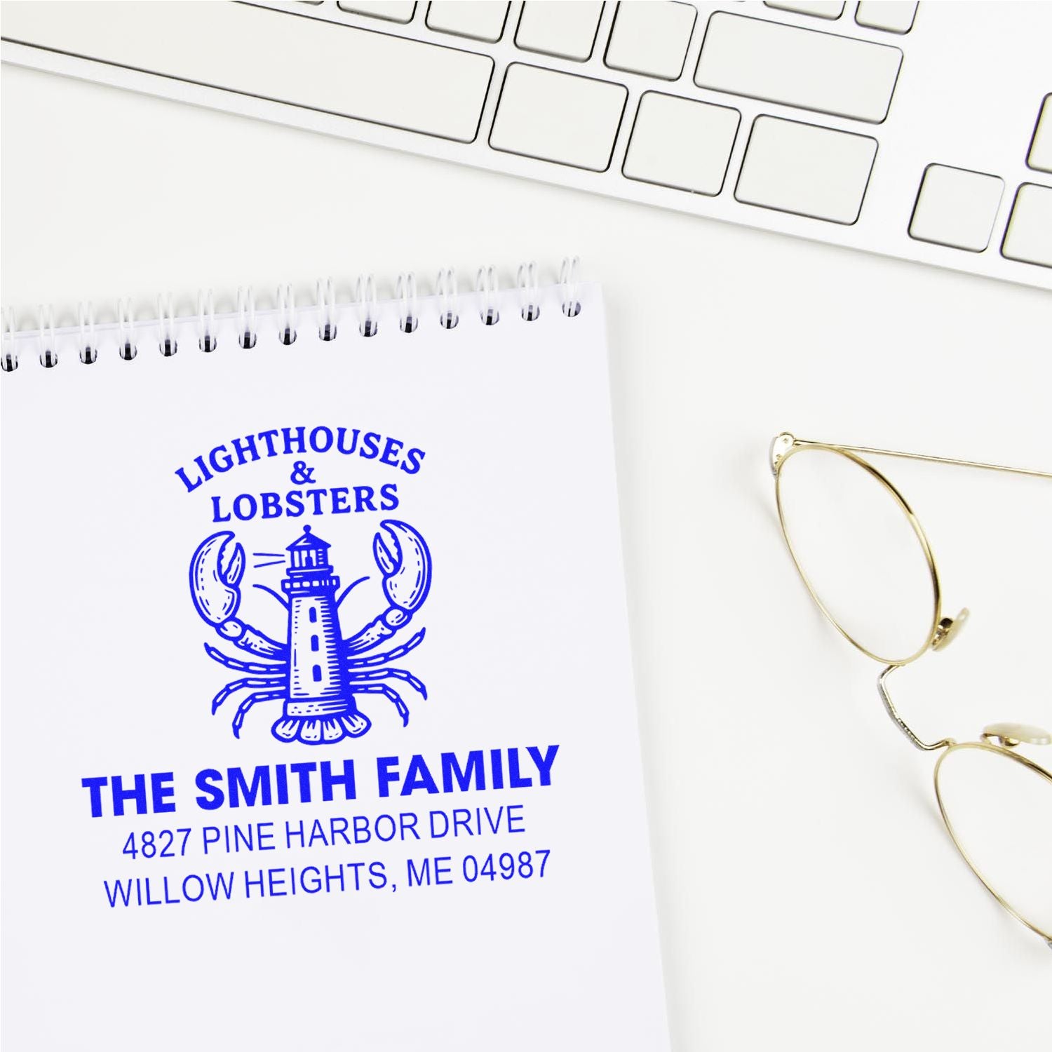 Custom nautical rubber stamp with lighthouse and lobster design for The Smith Family address, blue ink on notebook.