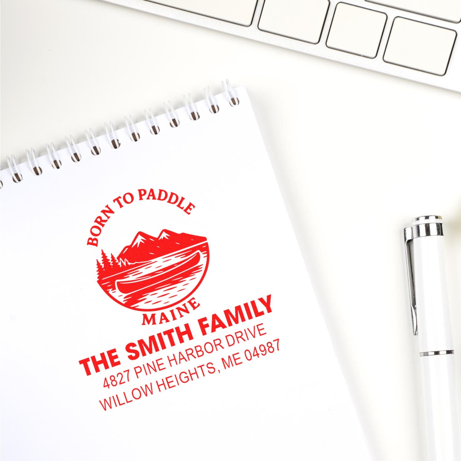 Red custom address rubber stamp impression with canoe graphic for family stationery and mailings.