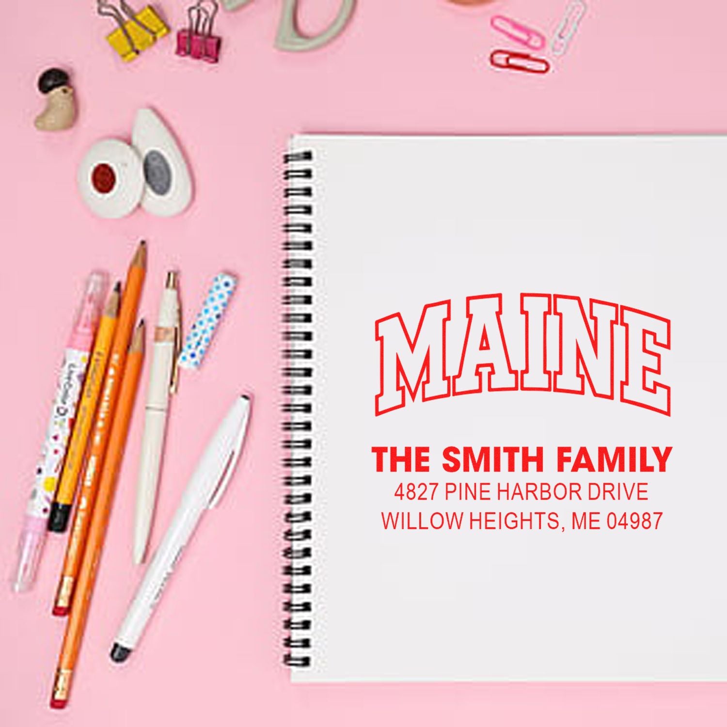 Custom rubber address stamp with The Smith Family return address, Maine design displayed on notebook.