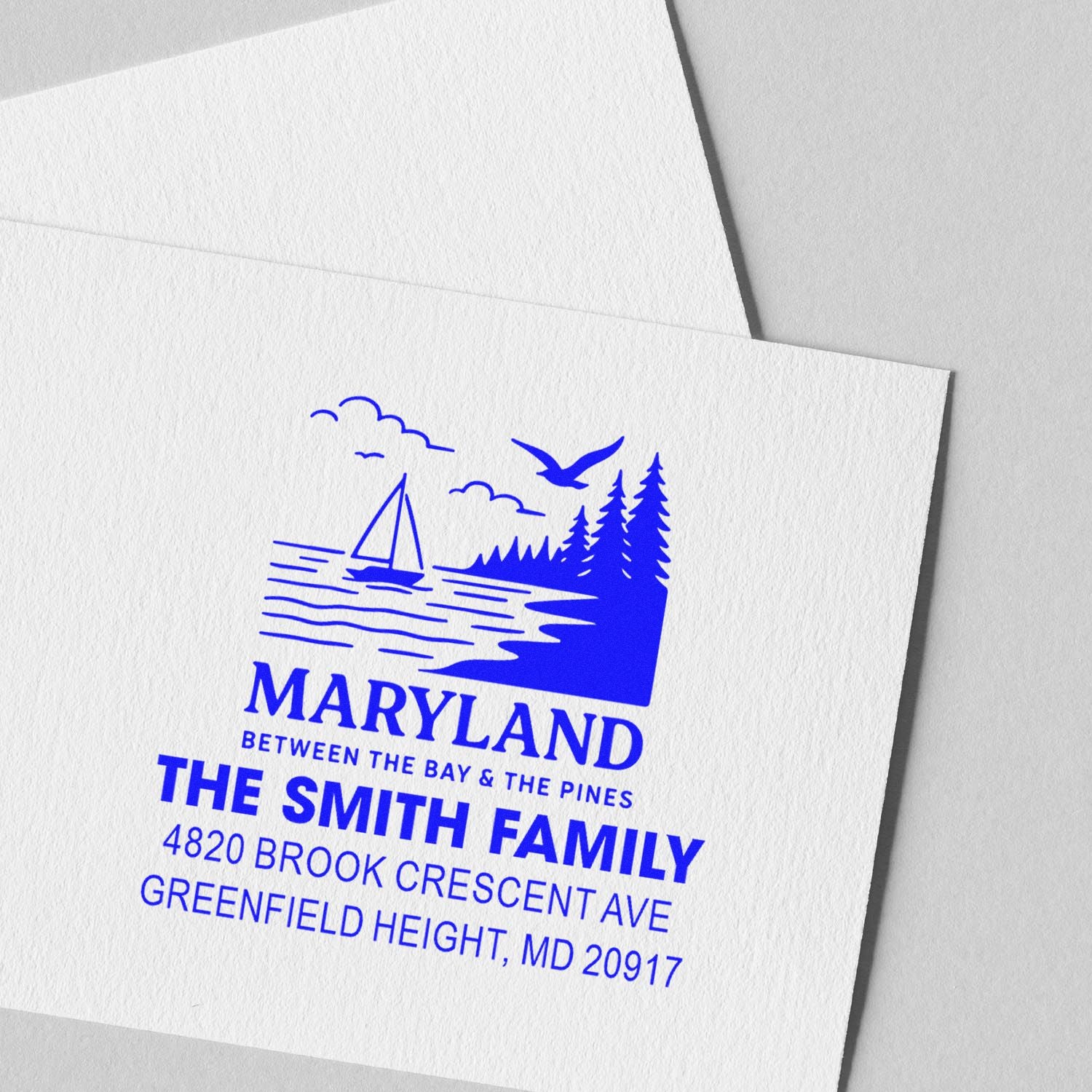 Custom return address rubber stamp for The Smith Family, with Maryland sailboat, pine trees, and blue ink.
