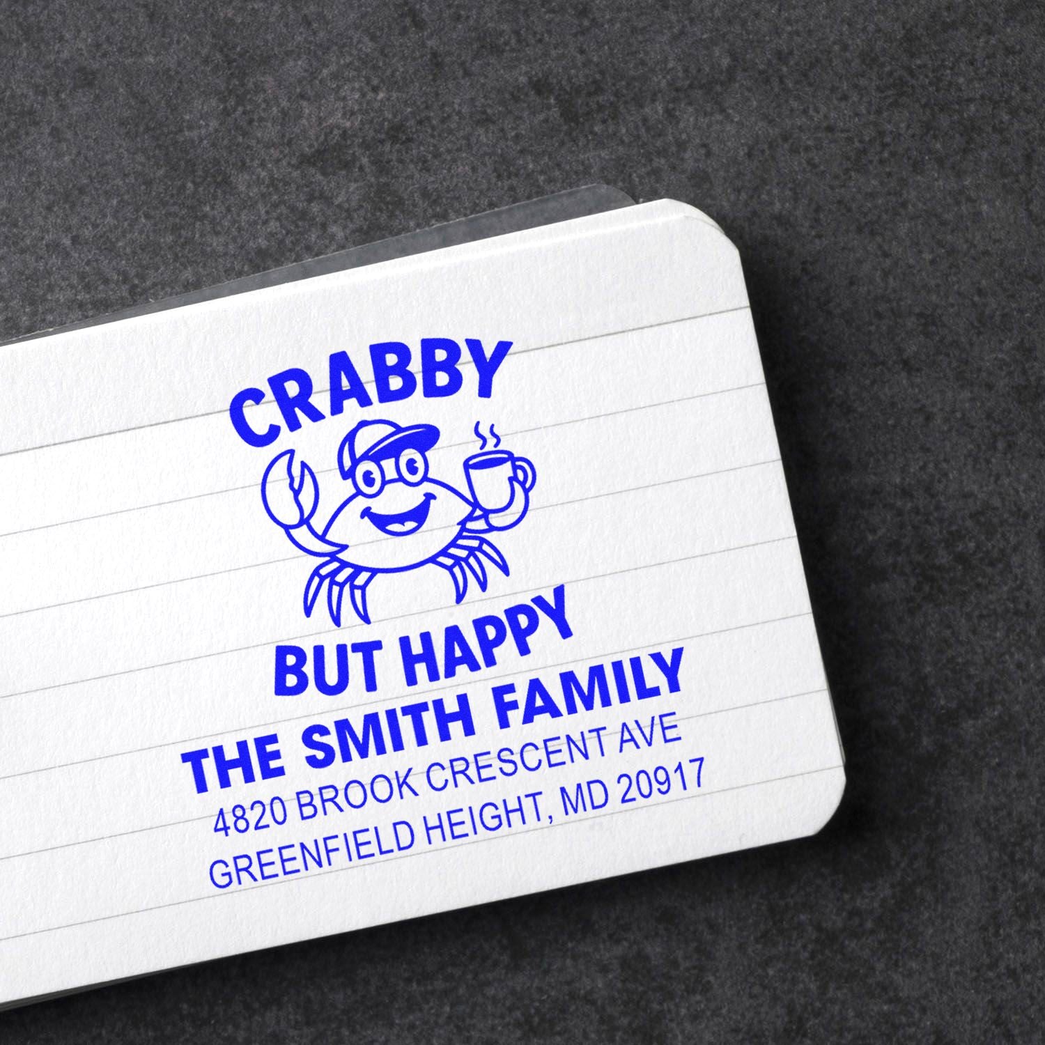 Custom rubber address stamp impression for The Smith Family with crab design, slogan, and mailing address in blue ink.
