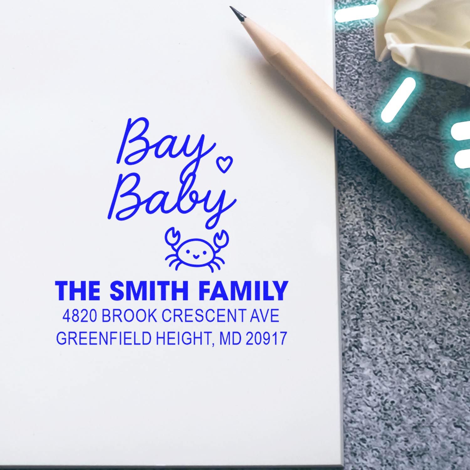 Custom return address rubber stamp with Bay Baby crab design and The Smith Family address on paper.
