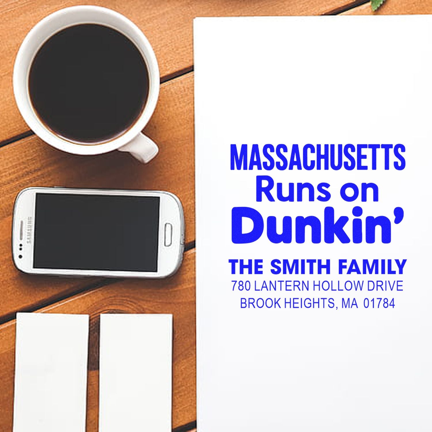 Custom Massachusetts address rubber stamp mockup featuring Runs on Dunkin family text, shown with coffee and phone.