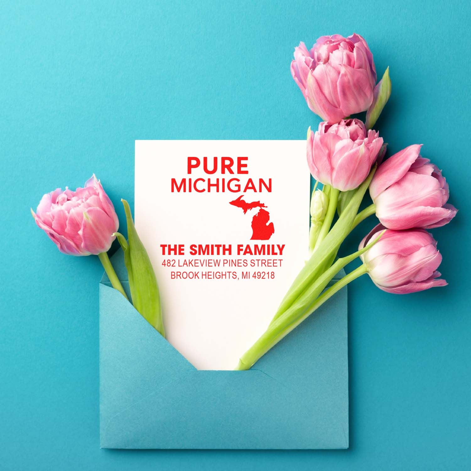 Custom Pure Michigan return address rubber stamp with family name and address, shown with pink tulips in a blue envelope.