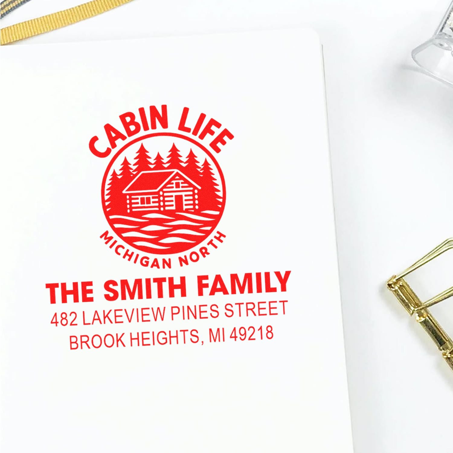 Custom cabin life rubber stamp with family name and address, featuring a red cabin and pine tree design for personalized mail.