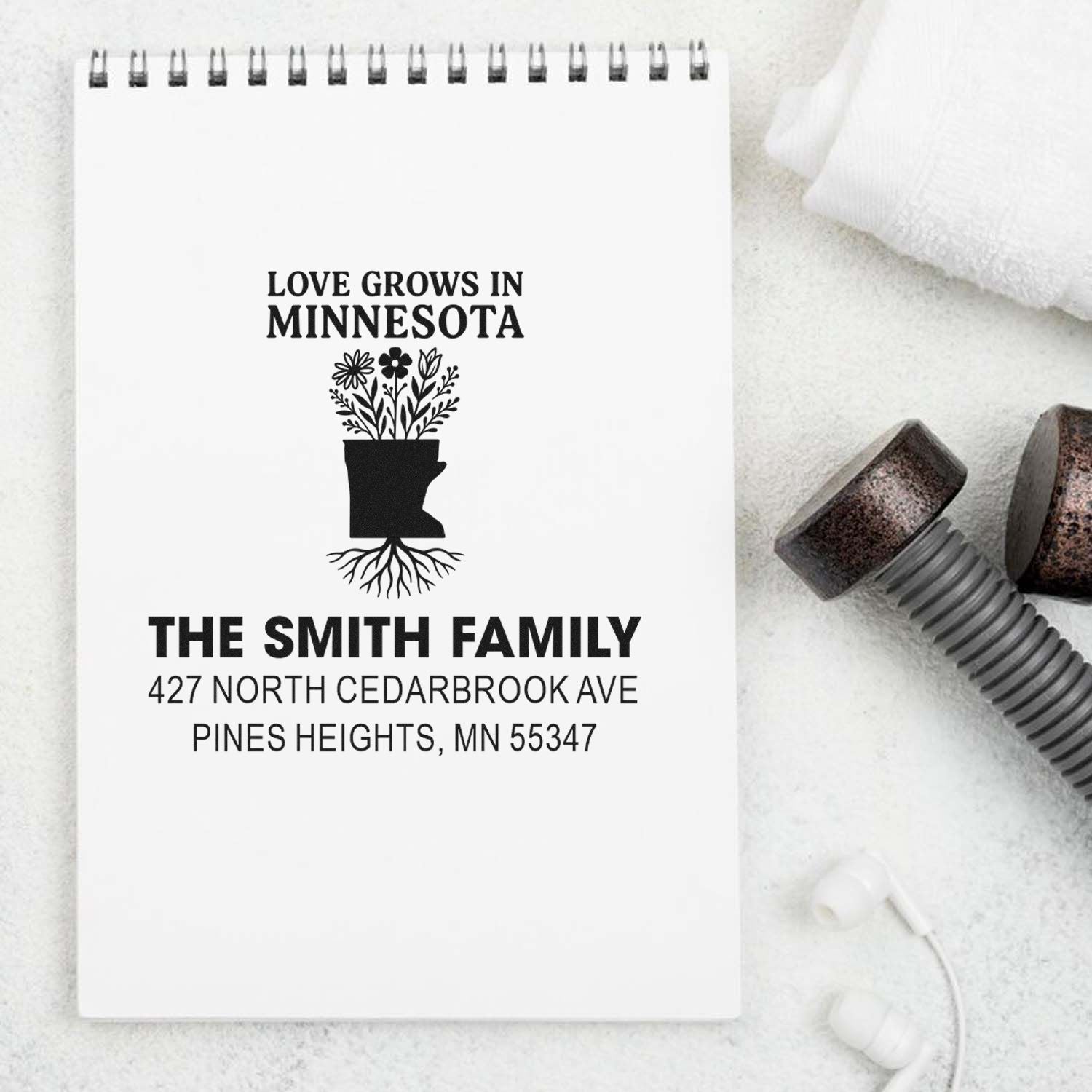 Custom Minnesota return address rubber stamp with floral state design for The Smith Family, shown on a notebook.