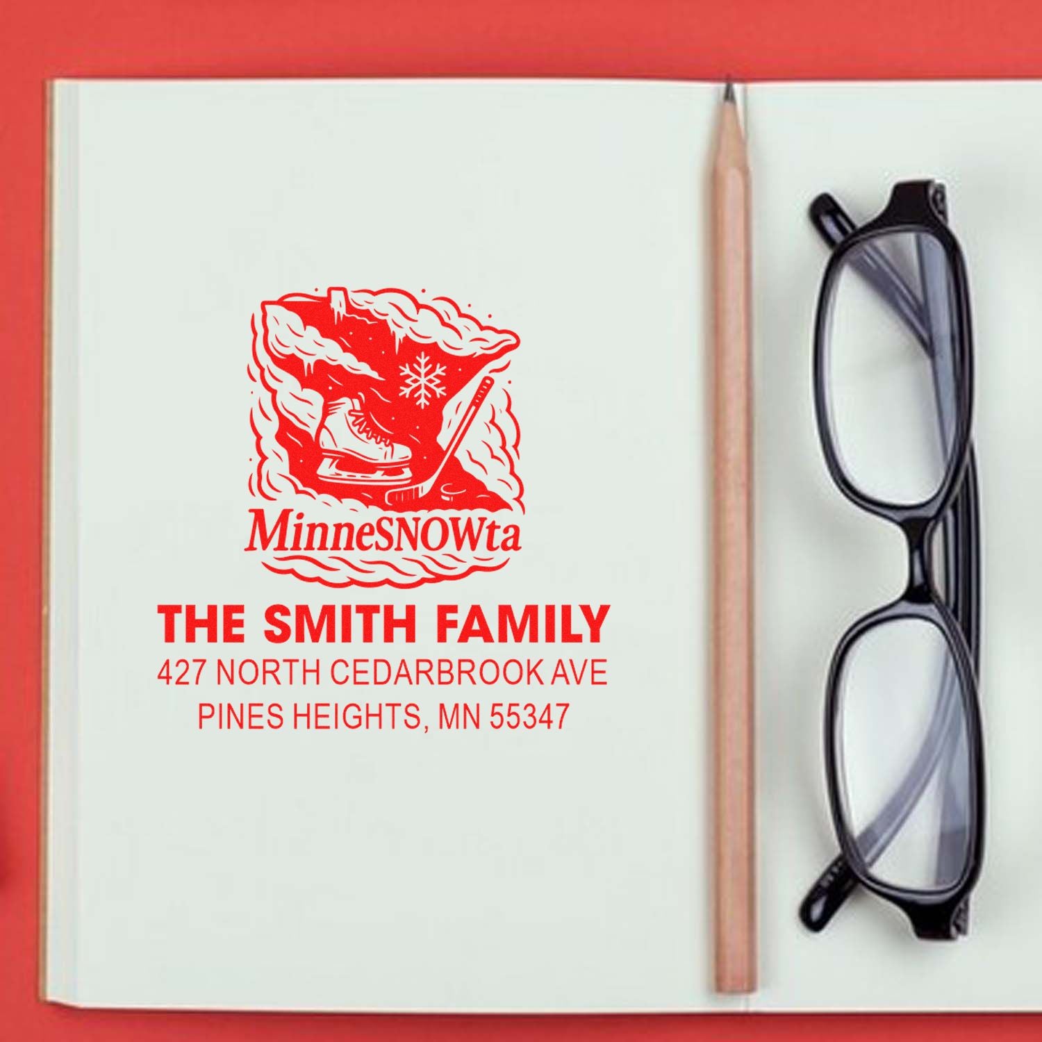 Custom family address rubber stamp with Minnesota MinneSNOWta hockey design, shown stamped on a notebook page.