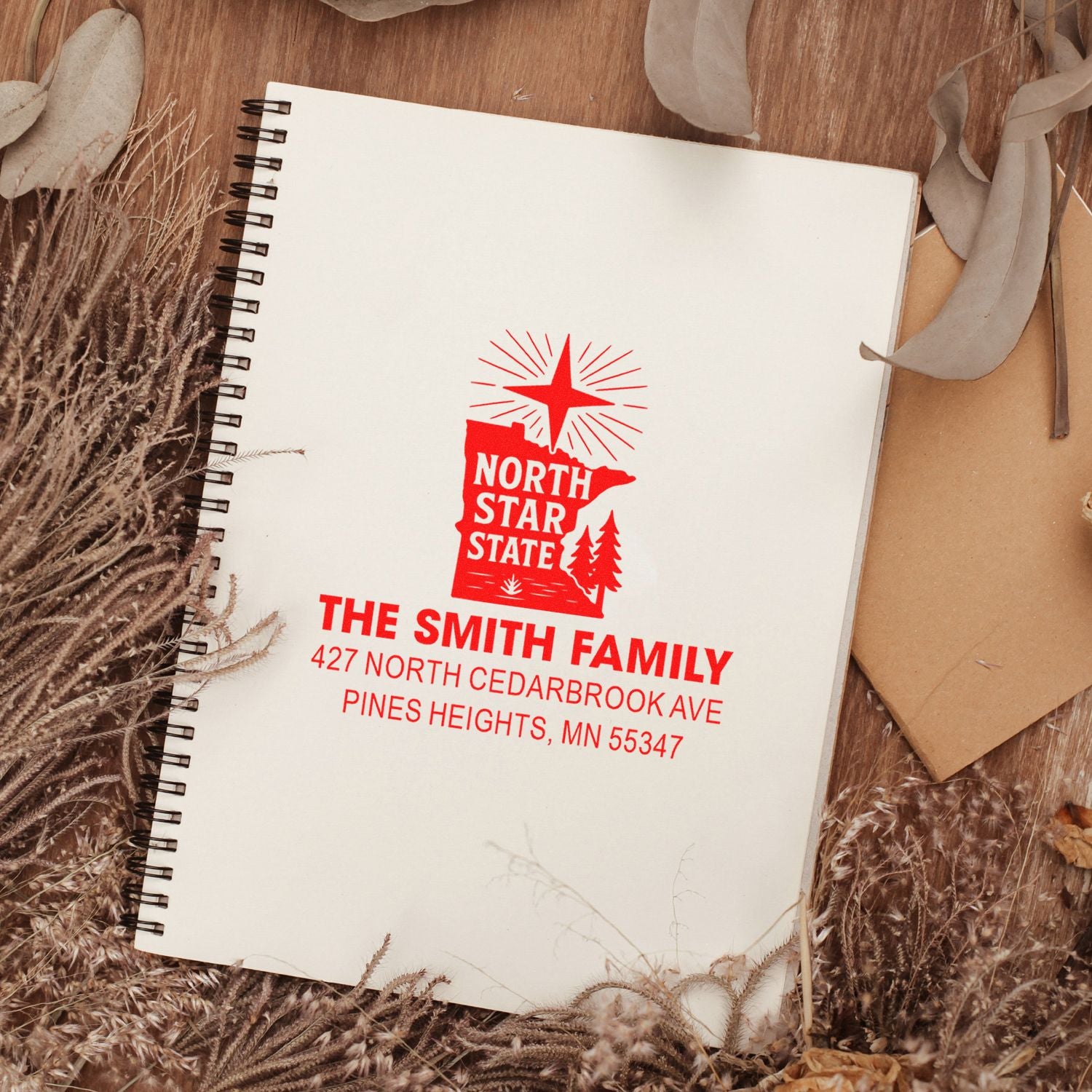 Custom red return address rubber stamp on notebook, featuring The Smith Family and North Star State design.