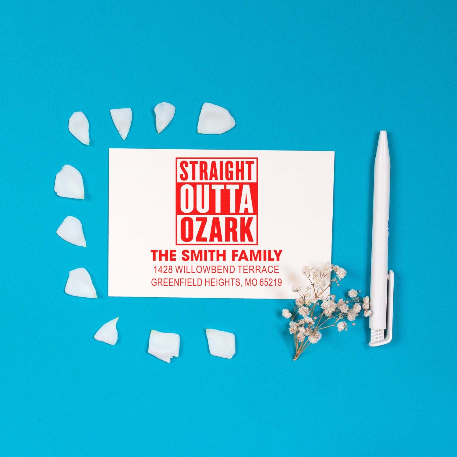 Custom rubber address stamp with Straight Outta Ozark design for The Smith Family, styled on a blue flat lay.