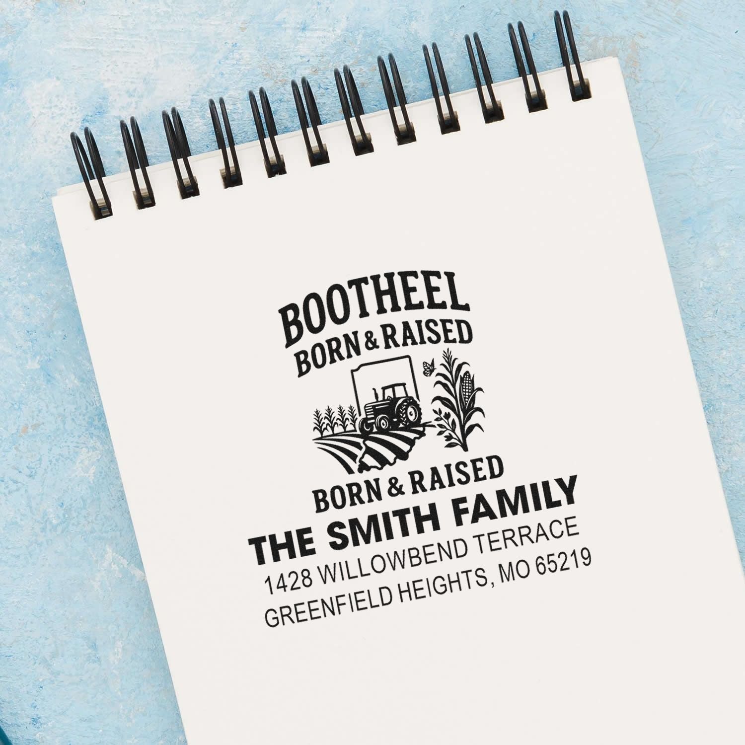 Custom farm family address rubber stamp with tractor logo and personalized name on a spiral notebook.