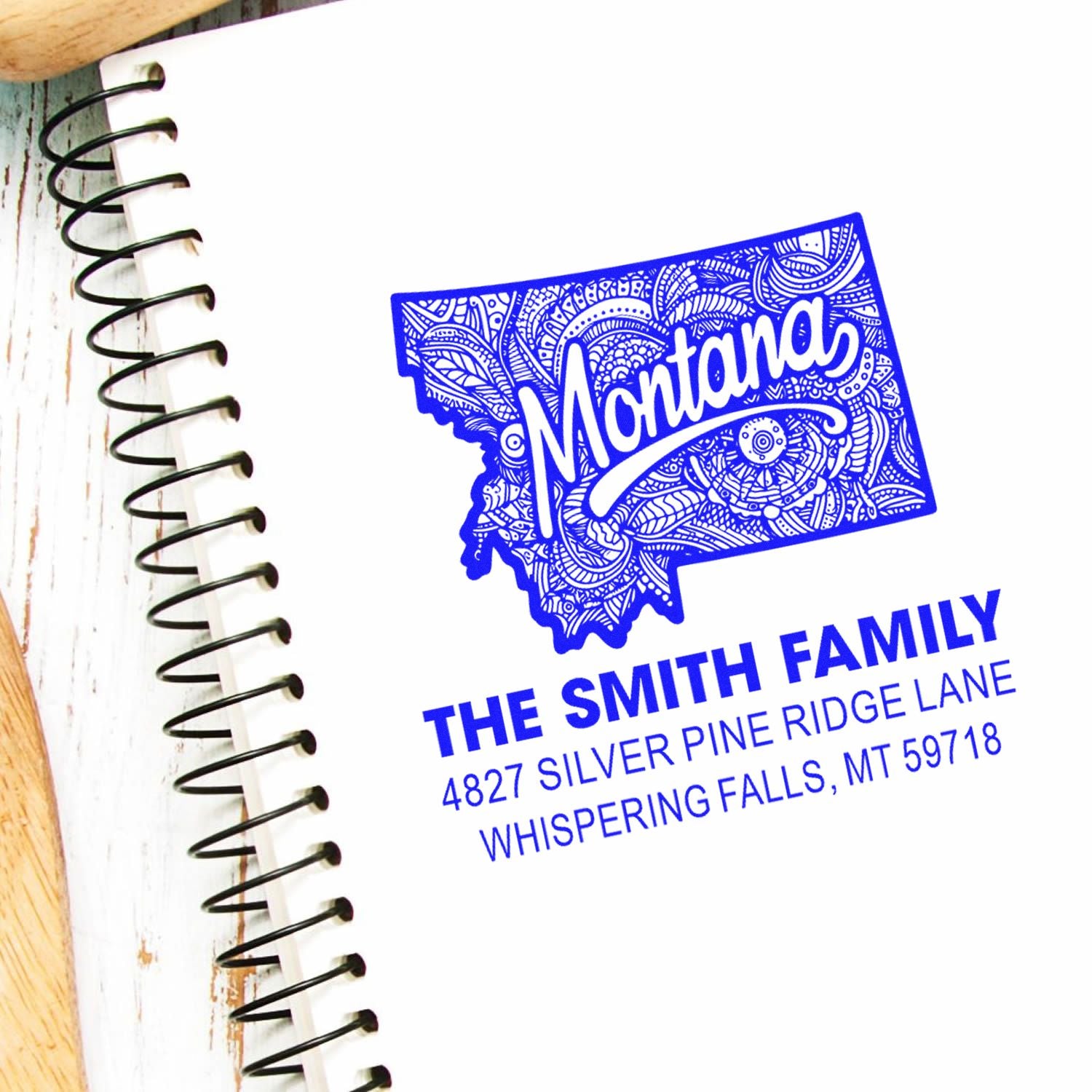 Custom Montana return address rubber stamp with state outline, shown on a notebook for personalized family mailing.