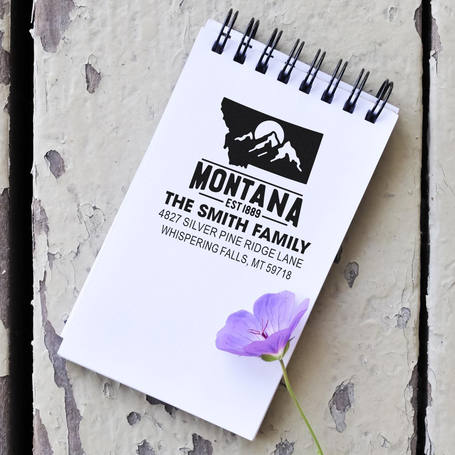 Custom Montana family return address rubber stamp on spiral notebook with mountain logo and address text.