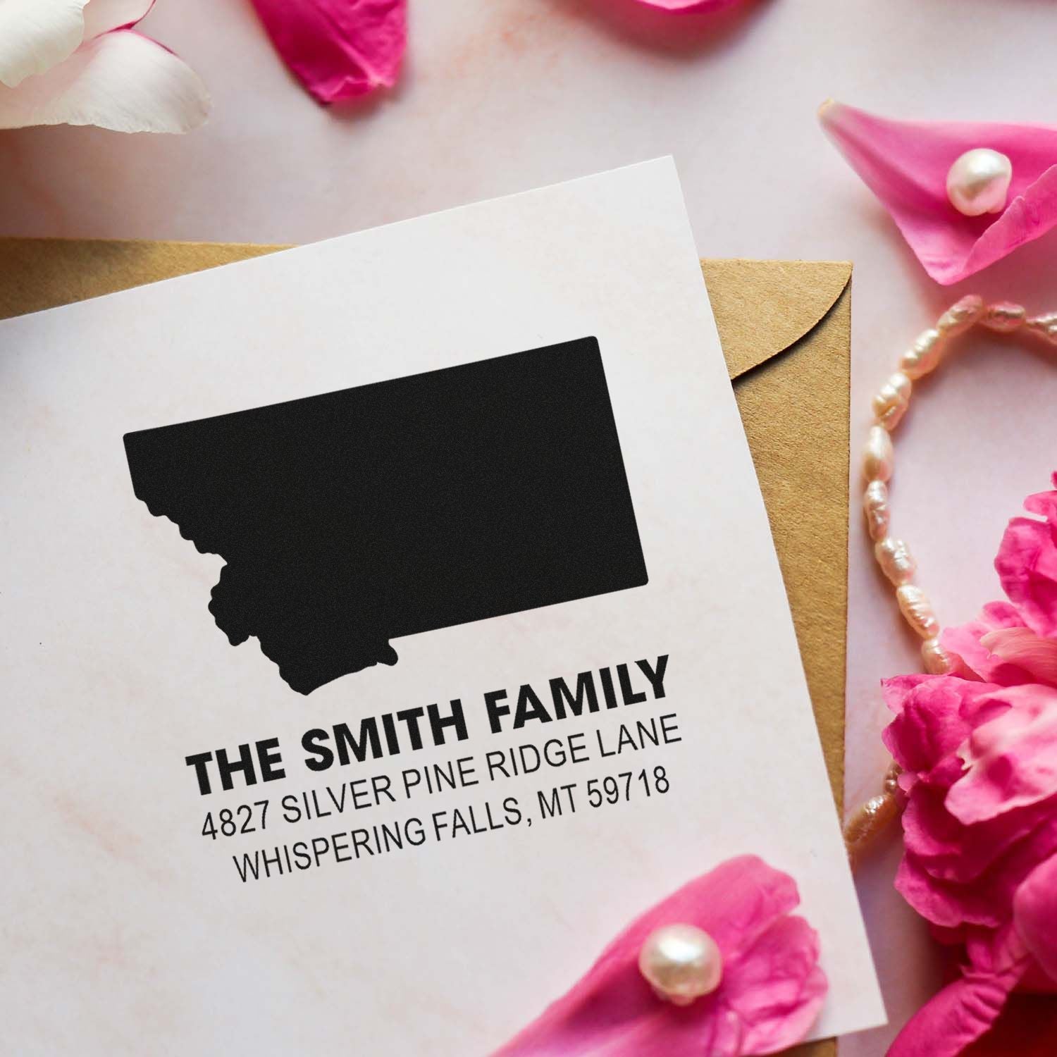 Custom return address rubber stamp on a wedding envelope with state silhouette, family name, and mailing address.