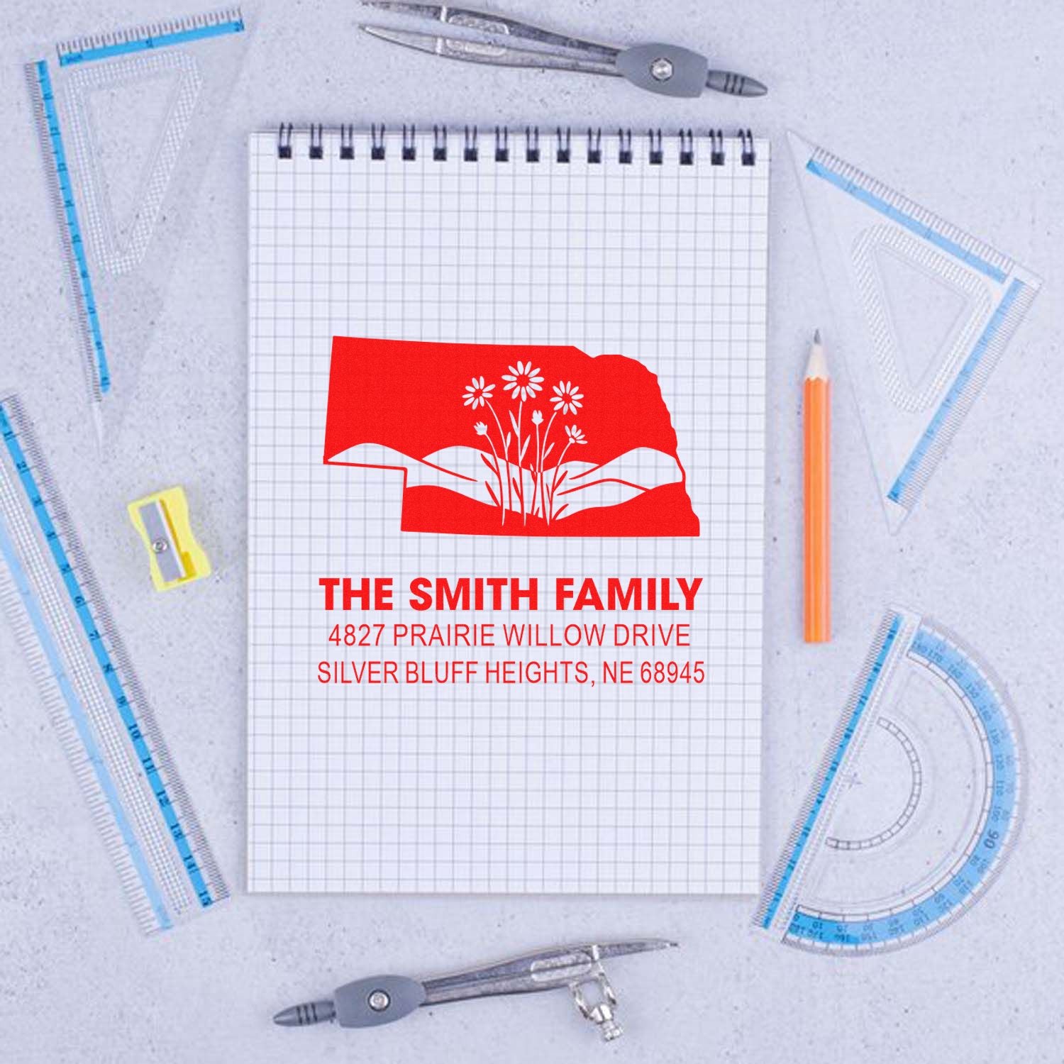 Custom Nebraska return address rubber stamp with family name, address, and floral state design on a notebook mockup.