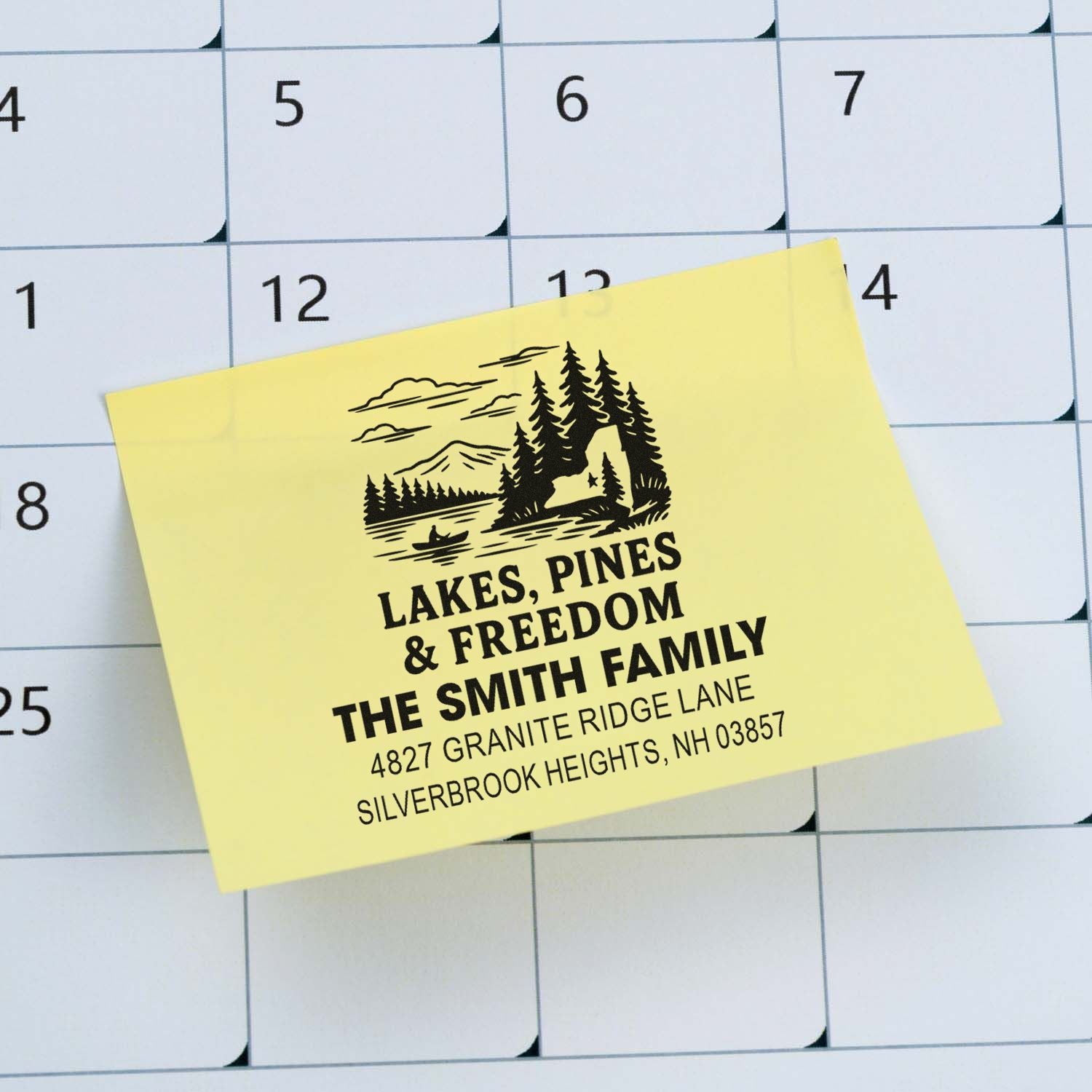 Personalized family rubber stamp with lakes, pines and freedom design, shown on a calendar for address labeling.