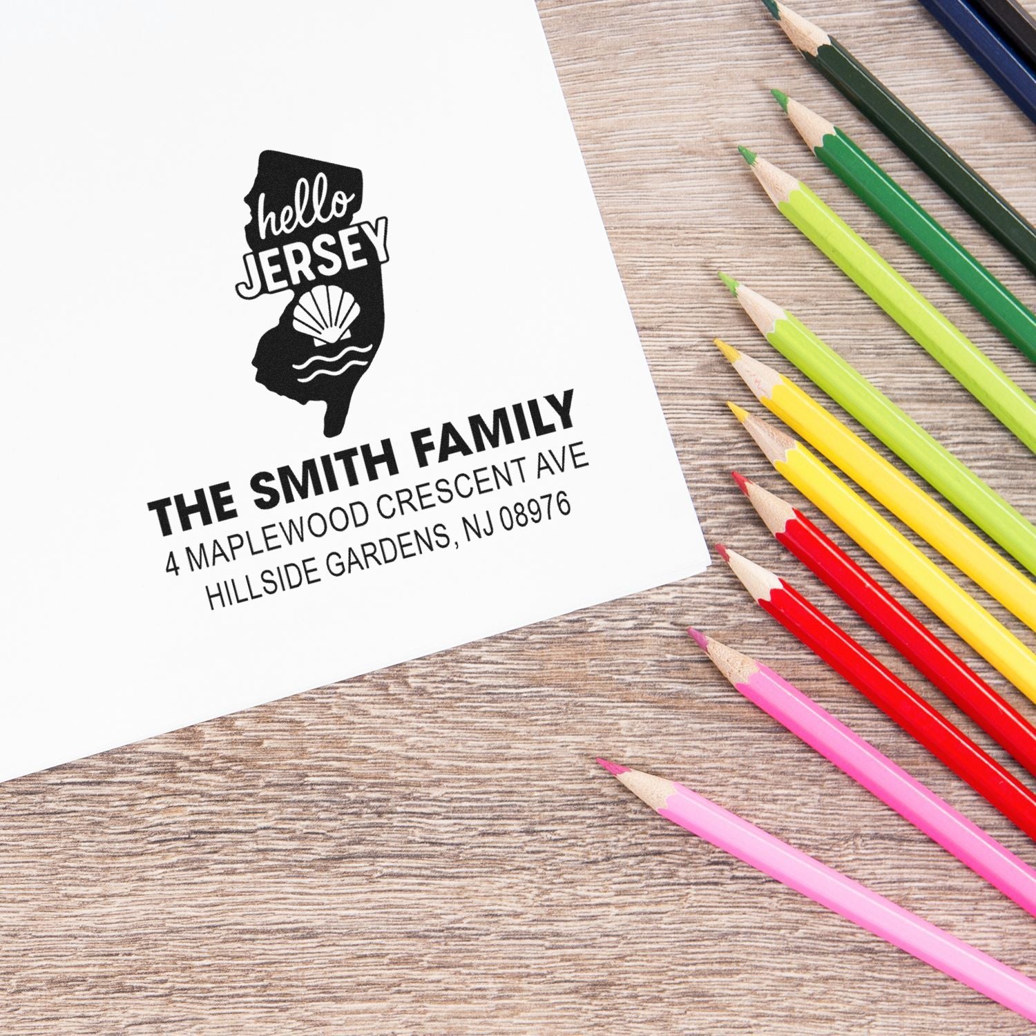Custom New Jersey return address rubber stamp with hello Jersey design and family address imprint, shown on paper with colored pencils.