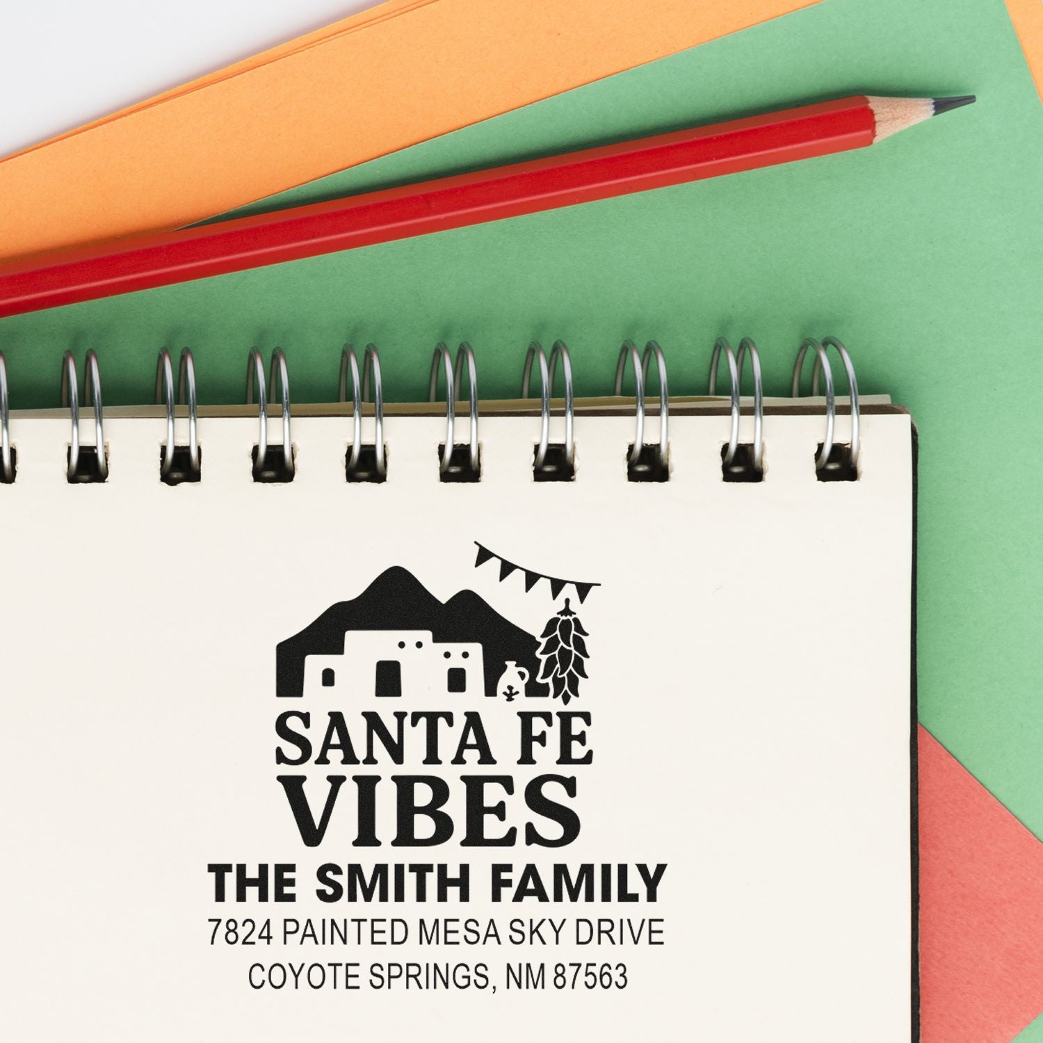 Custom Santa Fe Vibes rubber stamp with family name and address, shown on a notebook page with a pencil.