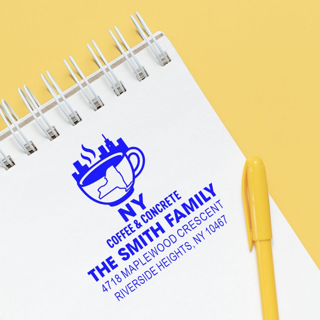 Custom business rubber stamp logo on notebook with NY Coffee & Concrete, The Smith Family, and address details.