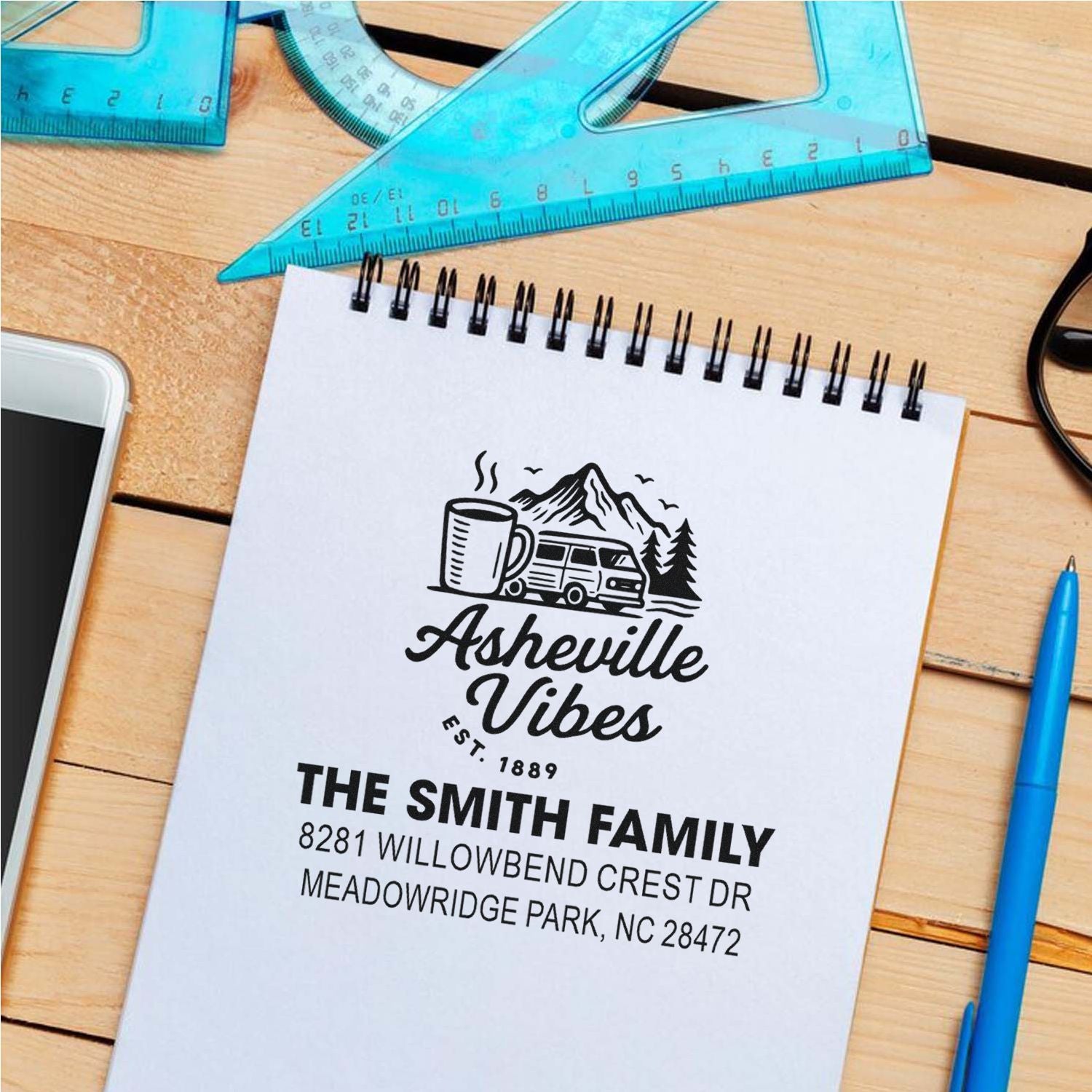 Custom rubber stamp design for personalized mailing, featuring Asheville Vibes logo and Smith family address on a notebook.