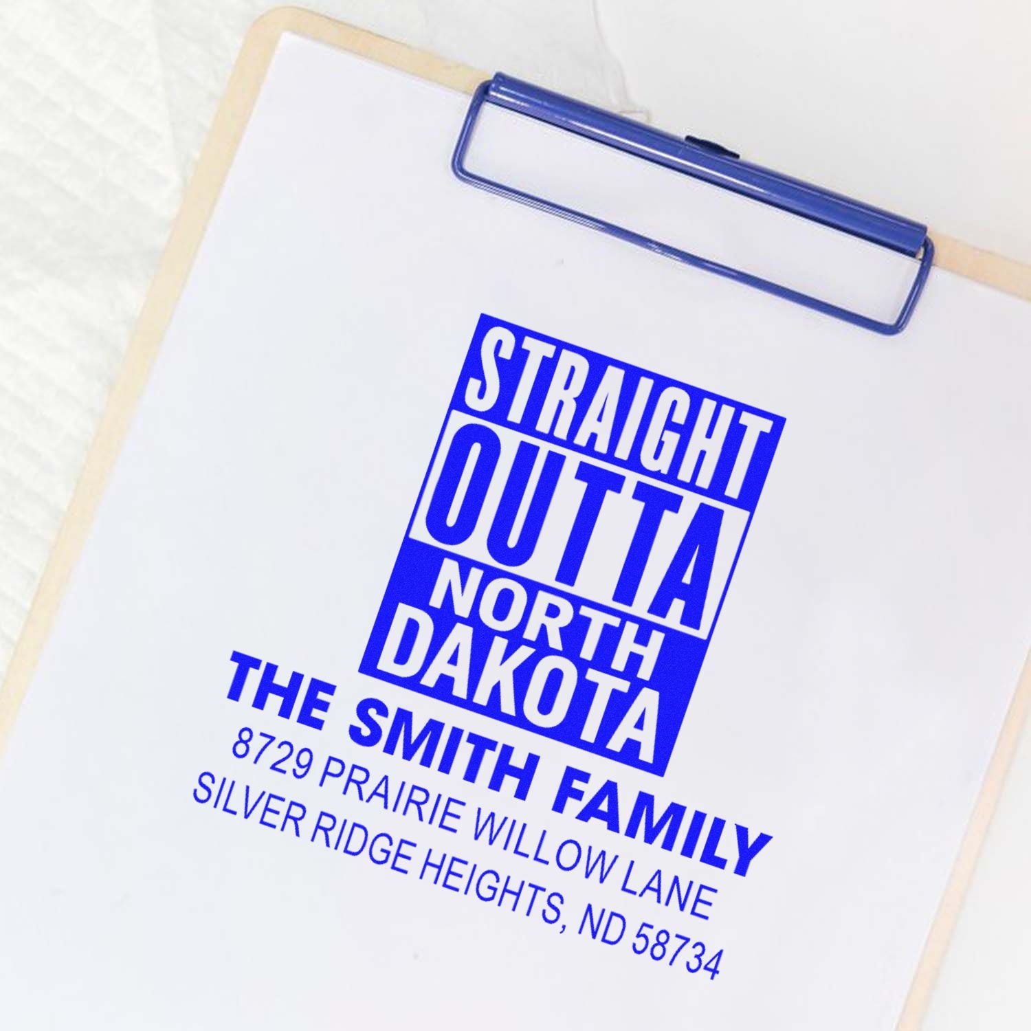 Custom family address rubber stamp imprint on clipboard, featuring a blue Straight Outta North Dakota return address design.