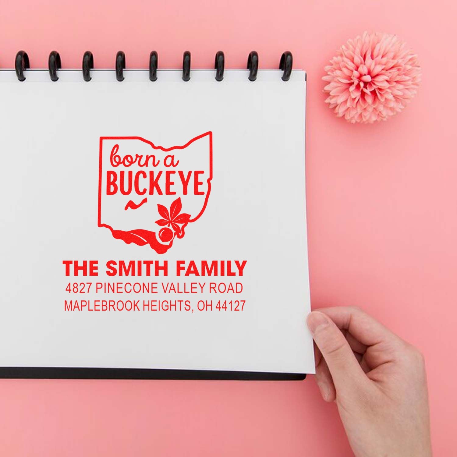 Custom Ohio family address rubber stamp with Born a Buckeye design and personalized name and address on a notebook.