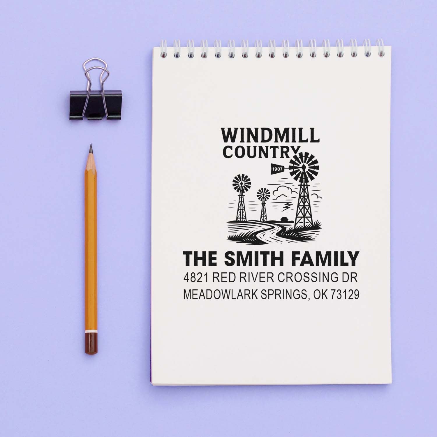 Custom family address rubber stamp impression with windmill farm design and The Smith Family name on a notebook.