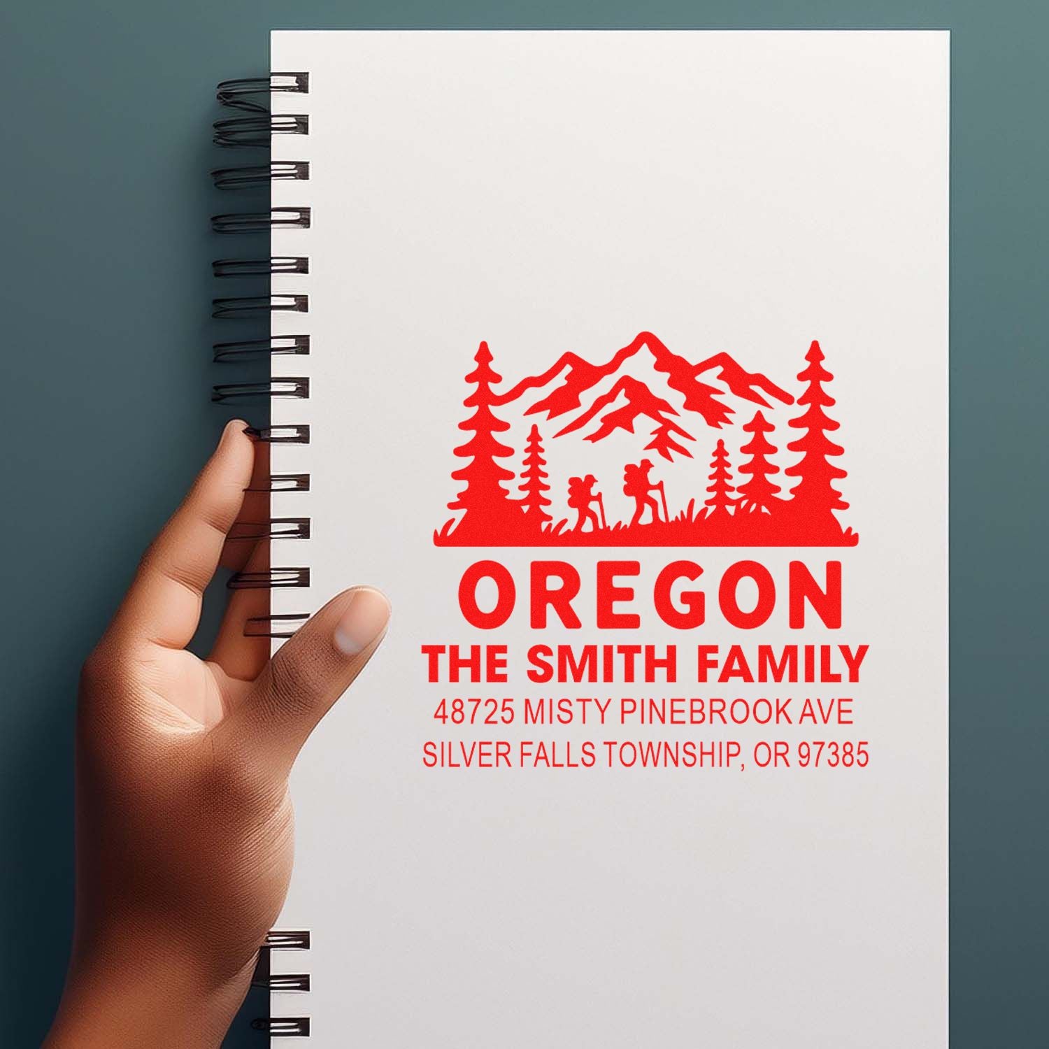 Personalized rubber stamp imprint on notebook featuring Oregon mountain and pine family address design for The Smith Family.