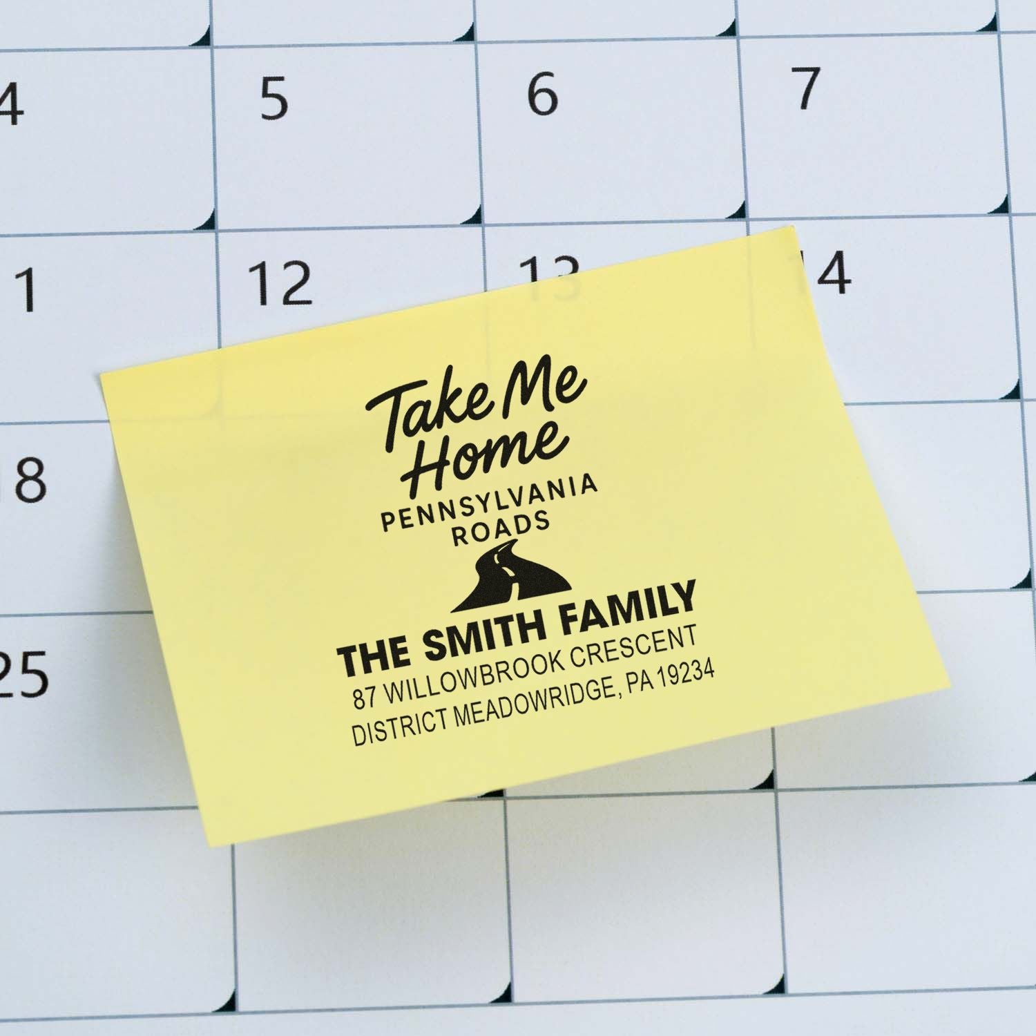 Personalized rubber address stamp design on sticky note over calendar, featuring Take Me Home Pennsylvania Roads and family address.