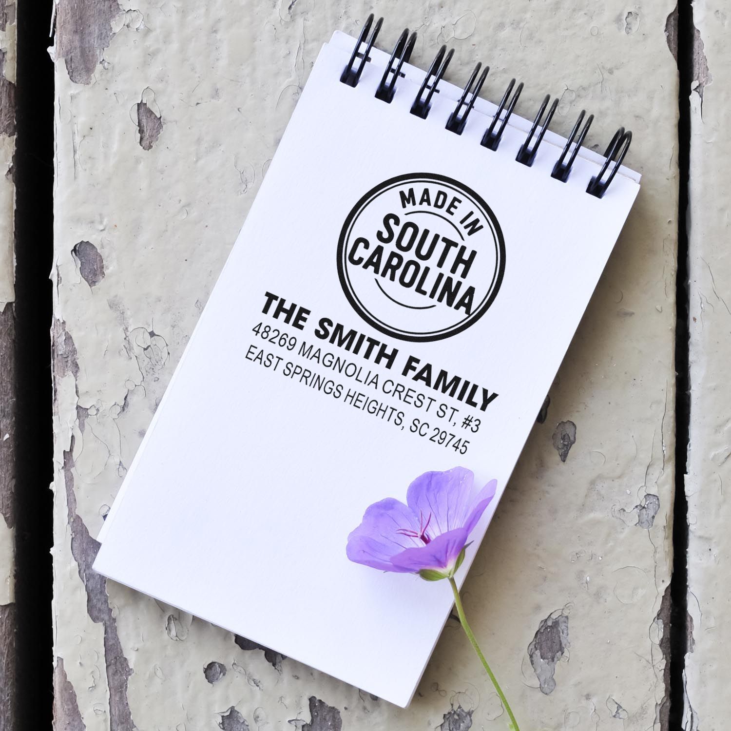 Custom rubber stamp mockup showing a South Carolina return address design on a spiral notebook for personalized mailing.