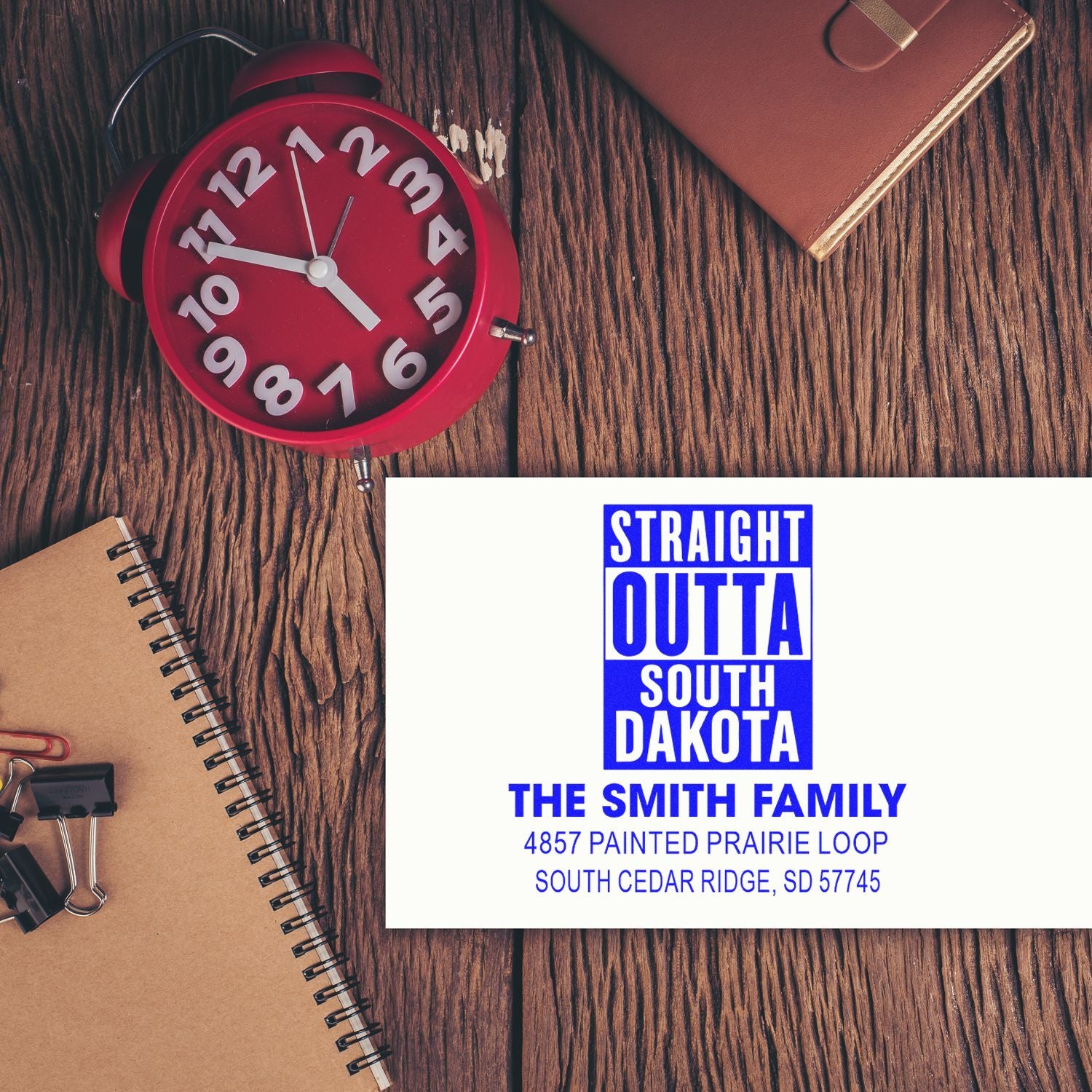 Personalized rubber stamp mockup for family mailing, featuring South Dakota address and custom name on a desk flat lay.