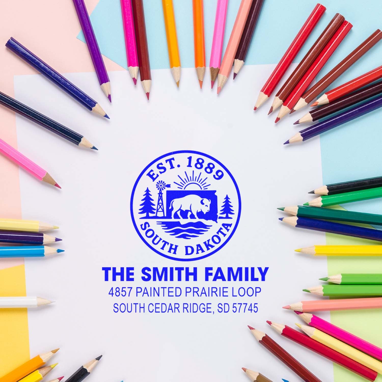 Custom rubber address stamp for The Smith Family with South Dakota state seal and return address, shown with colorful pencils.
