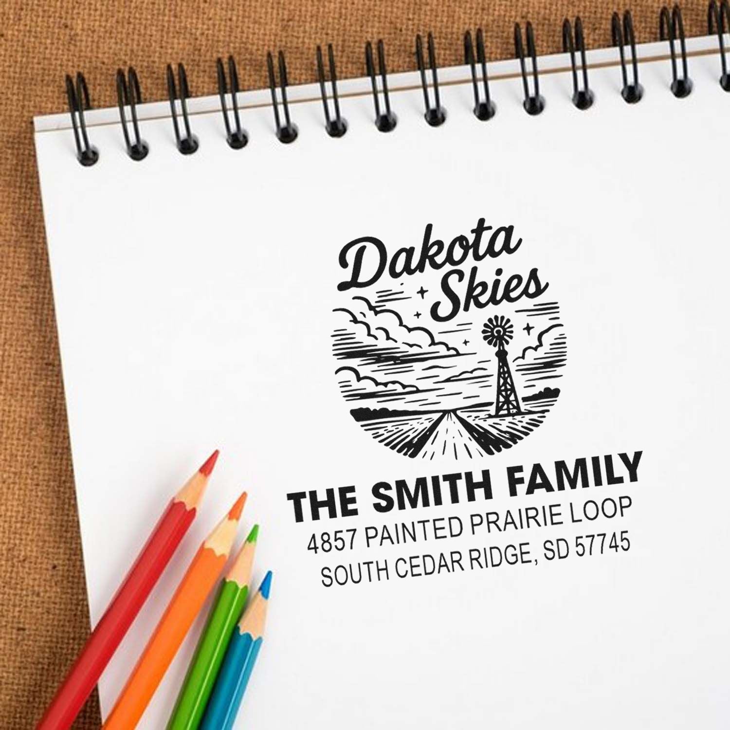 Custom rubber stamp with Dakota Skies logo and Smith family return address on a notebook page.