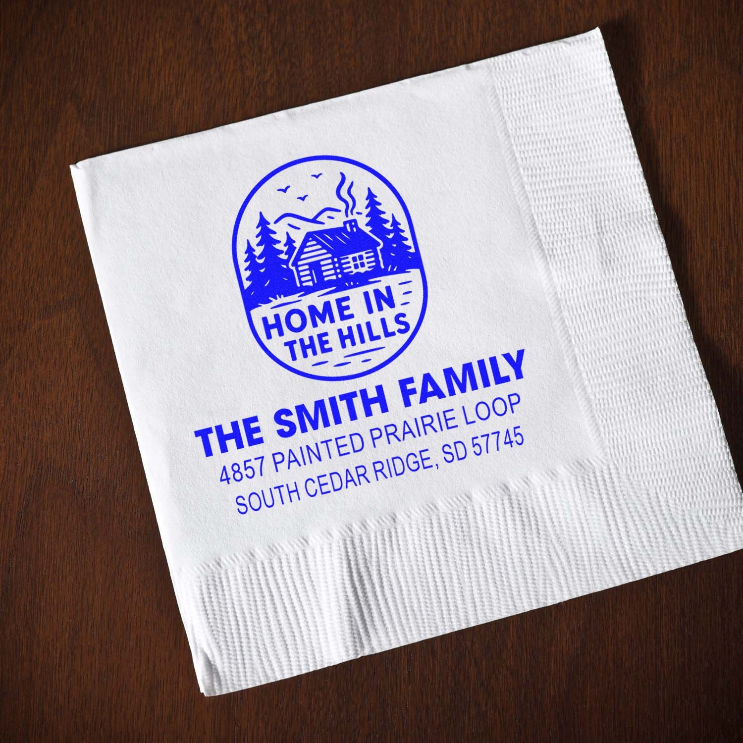 Custom rubber stamp on napkin with Home in the Hills cabin logo, The Smith Family name, and address for personalized branding.