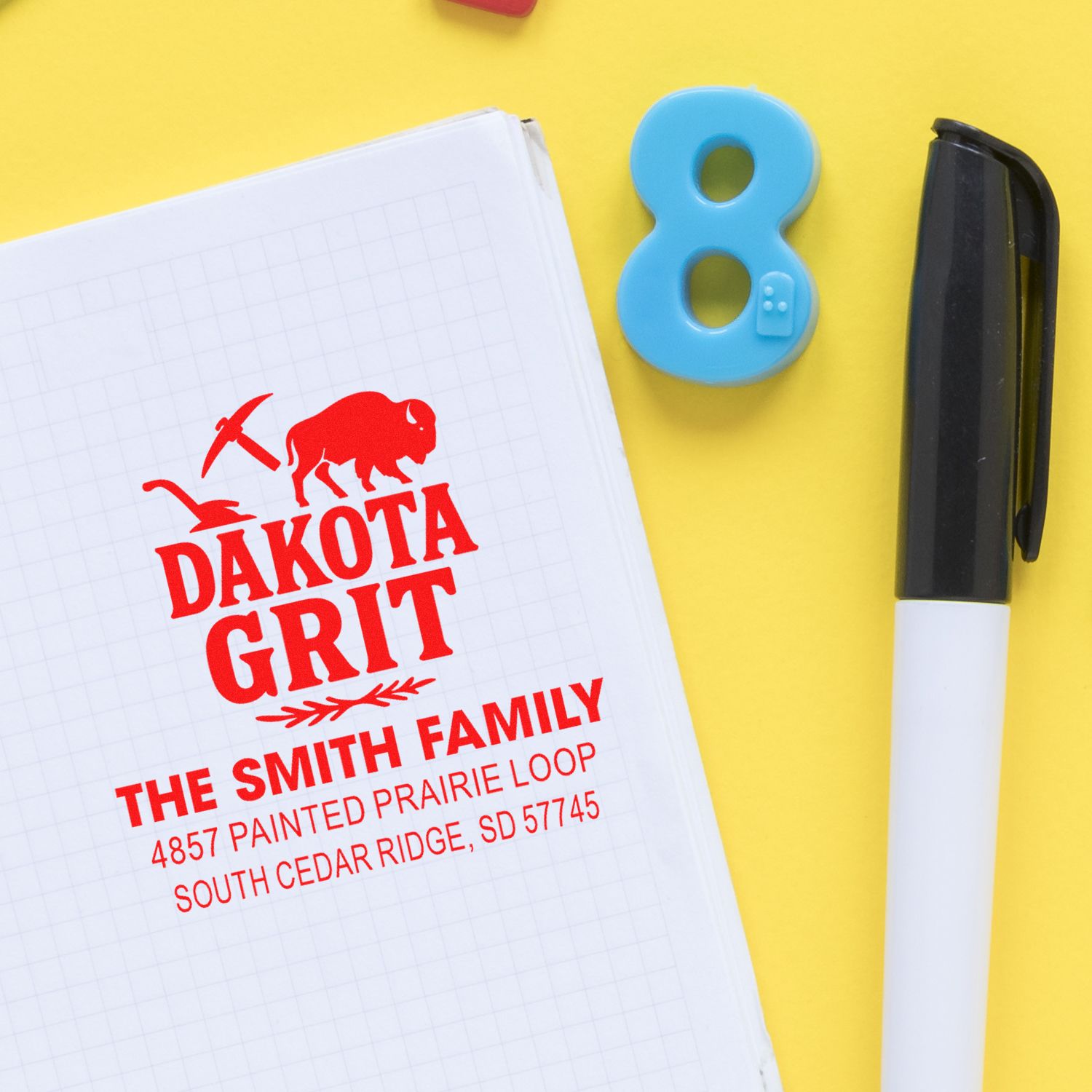Custom rubber address stamp with Dakota Grit logo and family name, ideal for personalized mailing, branding, and packaging.