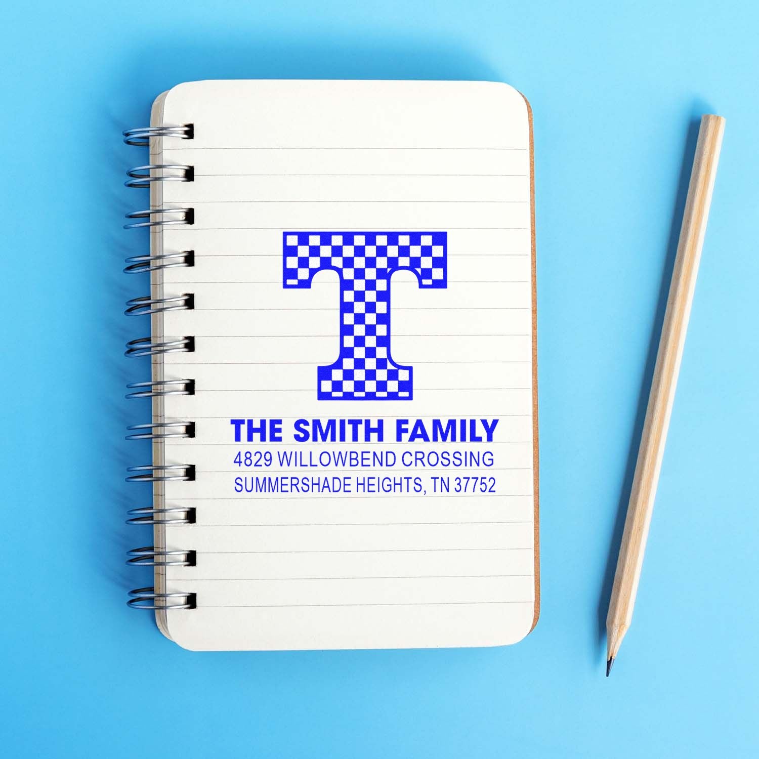 Custom return address rubber stamp with monogram T for The Smith Family, showing a personalized address on a notebook.