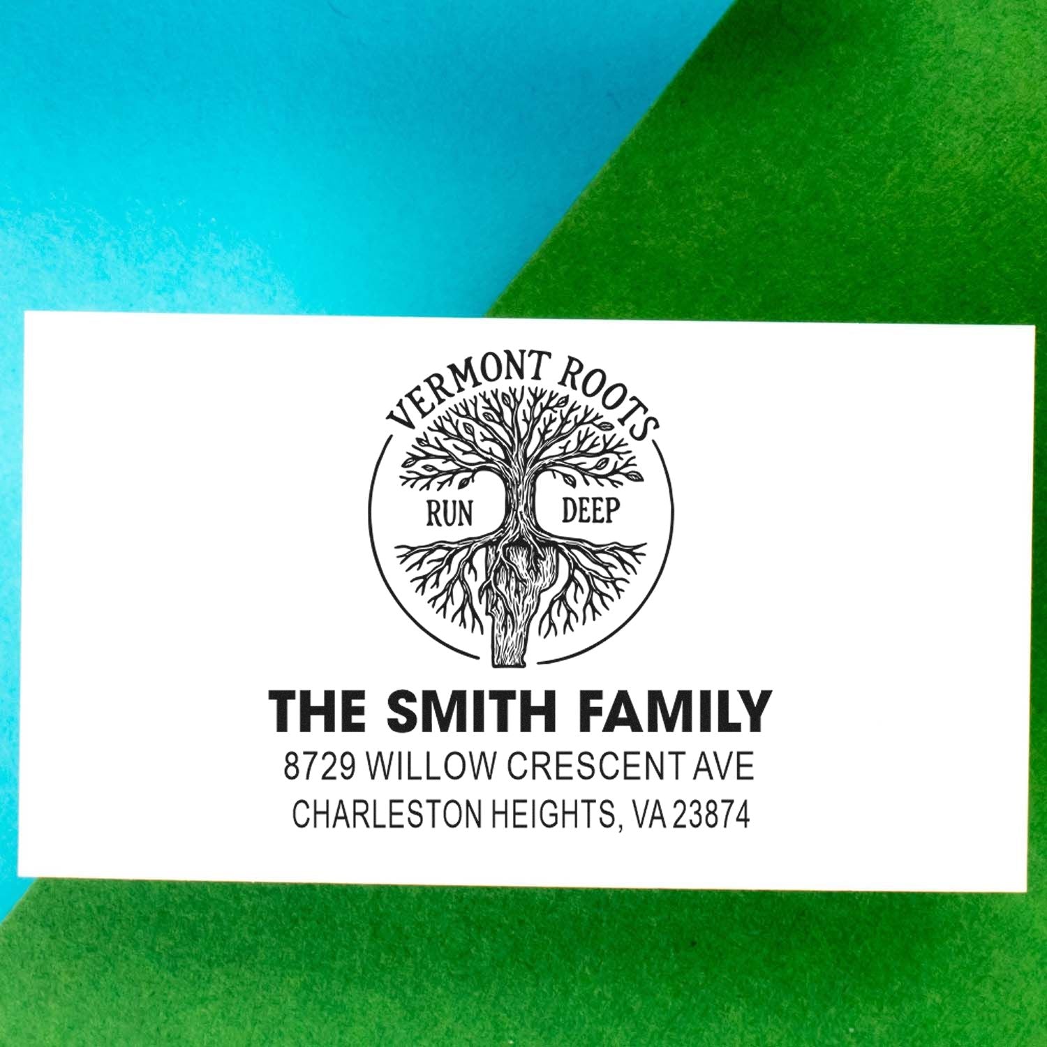 Custom return address stamp with tree logo, Vermont Roots Run Deep, The Smith Family, on white card over blue and green background.