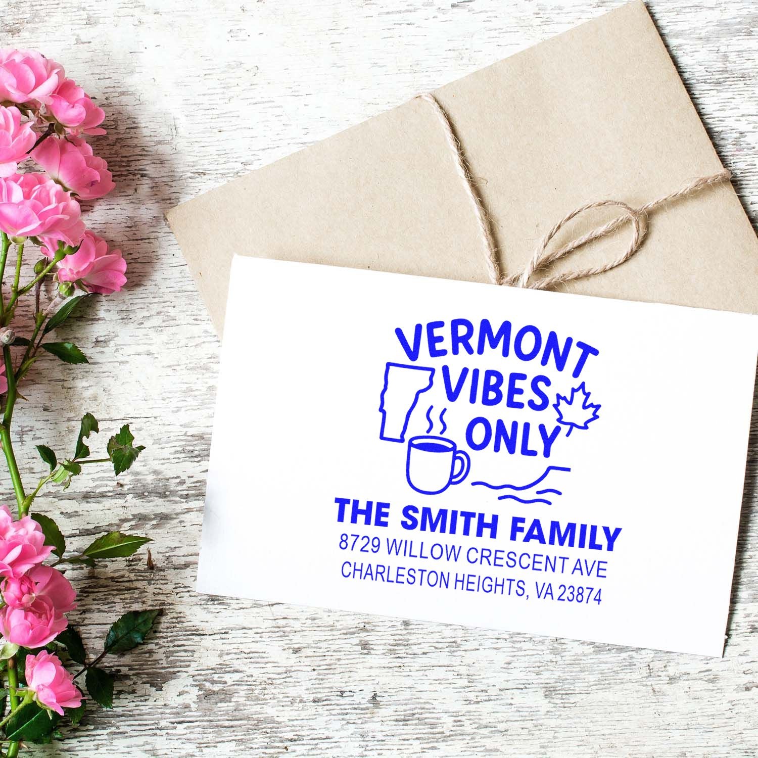 Custom Vermont Vibes Only address stamp with family name and address, shown on white card beside a kraft envelope and pink flowers on rustic wood.