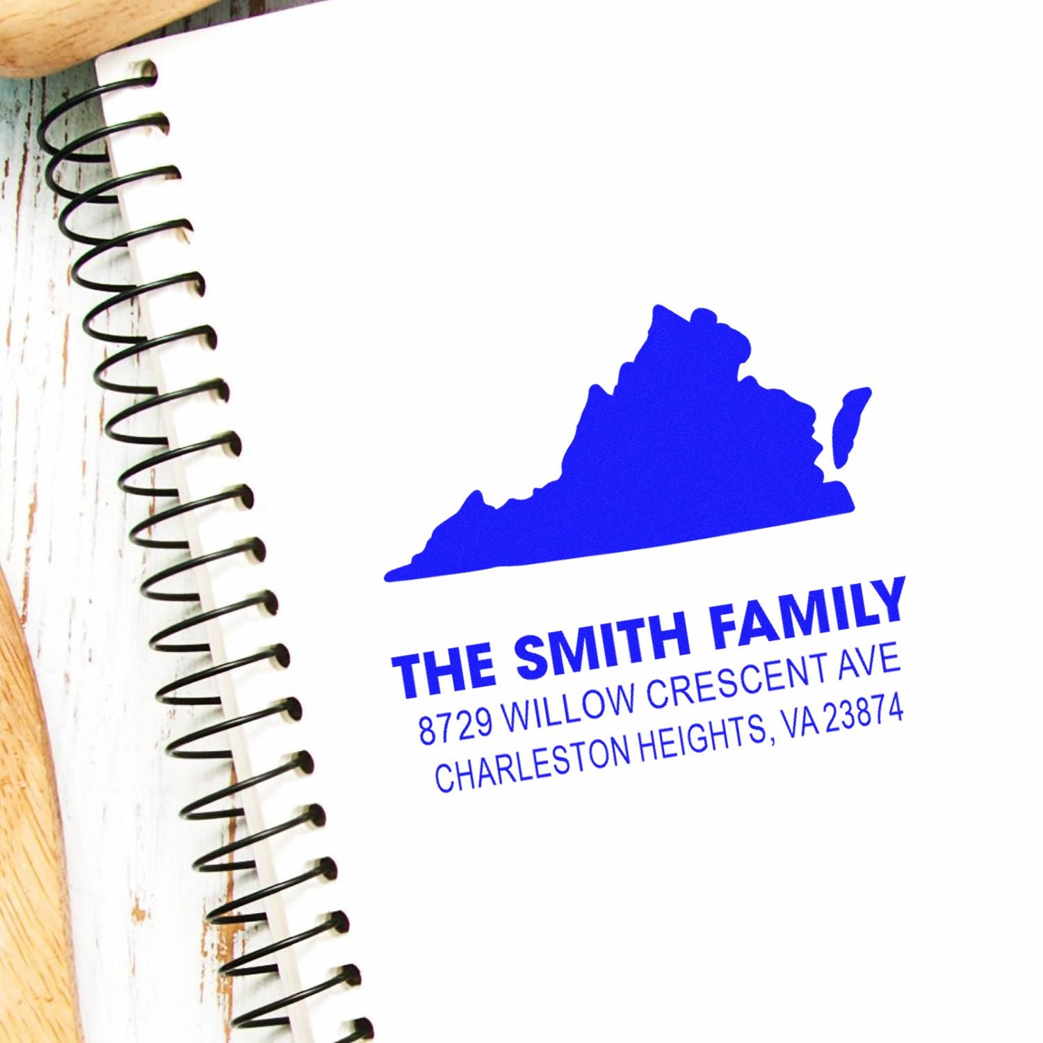 Blue custom family address stamp with Virginia silhouette and address on a spiral notebook page