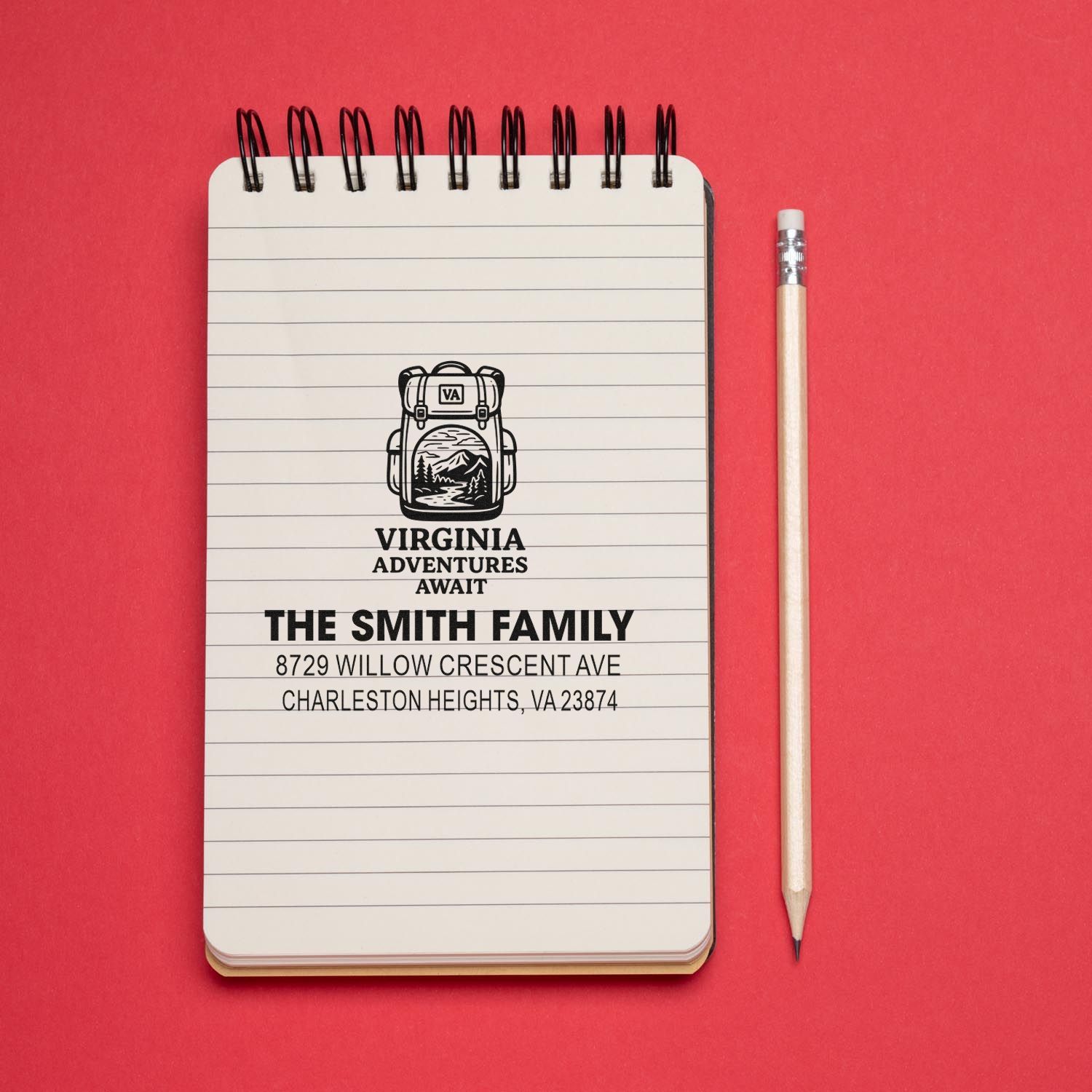 Personalized Virginia Adventures Await address stamp impression on lined notebook beside a pencil on a red background.