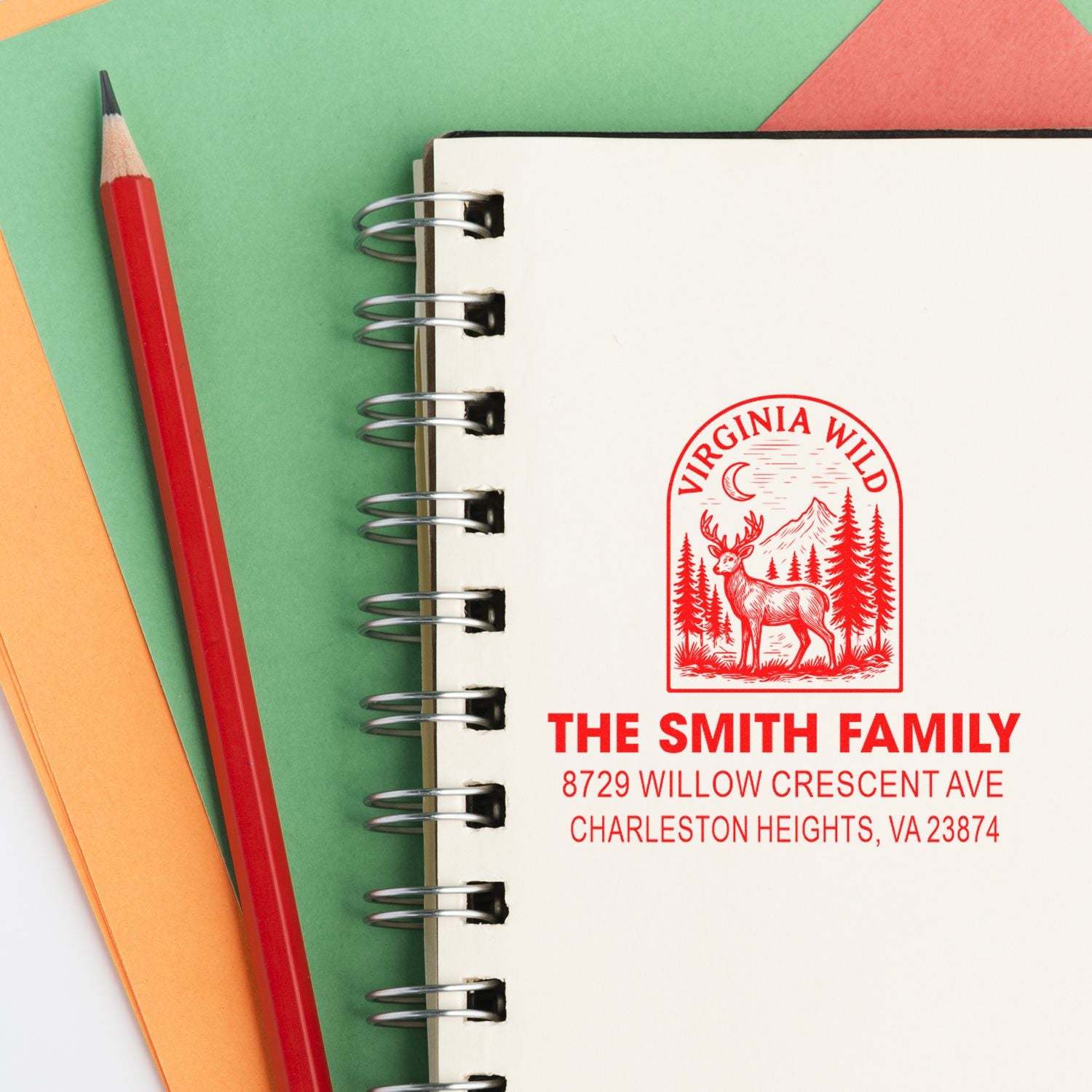 Custom red Virginia Wild address stamp on a spiral notebook with pencil and colored paper, featuring deer logo and The Smith Family address.
