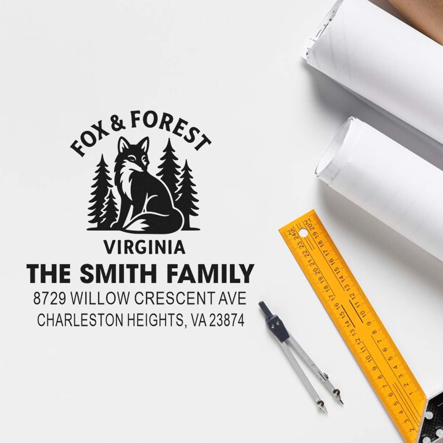 Custom Fox & Forest Virginia address stamp with family name and home address on white workspace, beside rulers, compass, and paper rolls