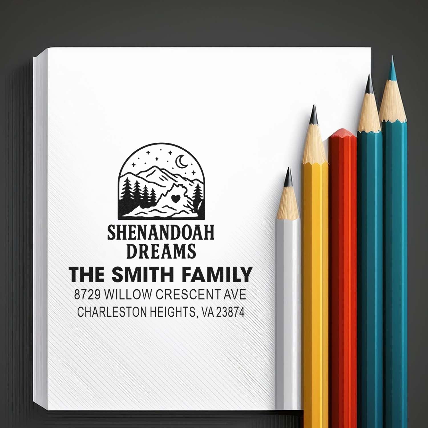 Custom family address stamp with Shenandoah Dreams mountain logo on white paper, beside colorful pencils, for The Smith Family in Charleston Heights, VA.