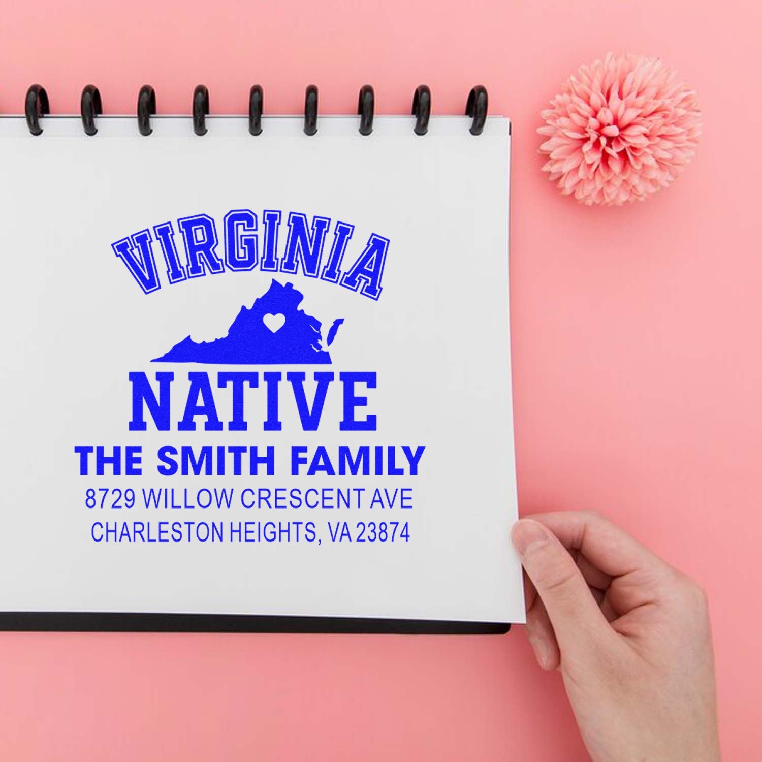 Custom Virginia Native family address stamp with state silhouette, held in a spiral notebook on a pink background with a flower accent.